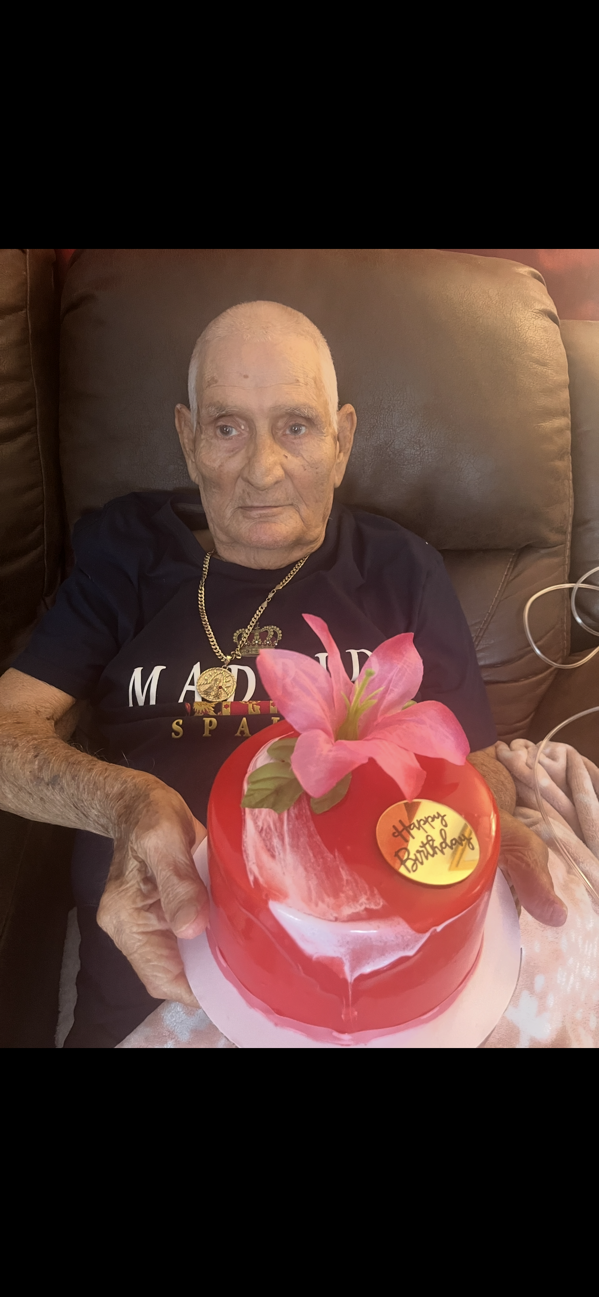 An old man sitting in a chair with a cake