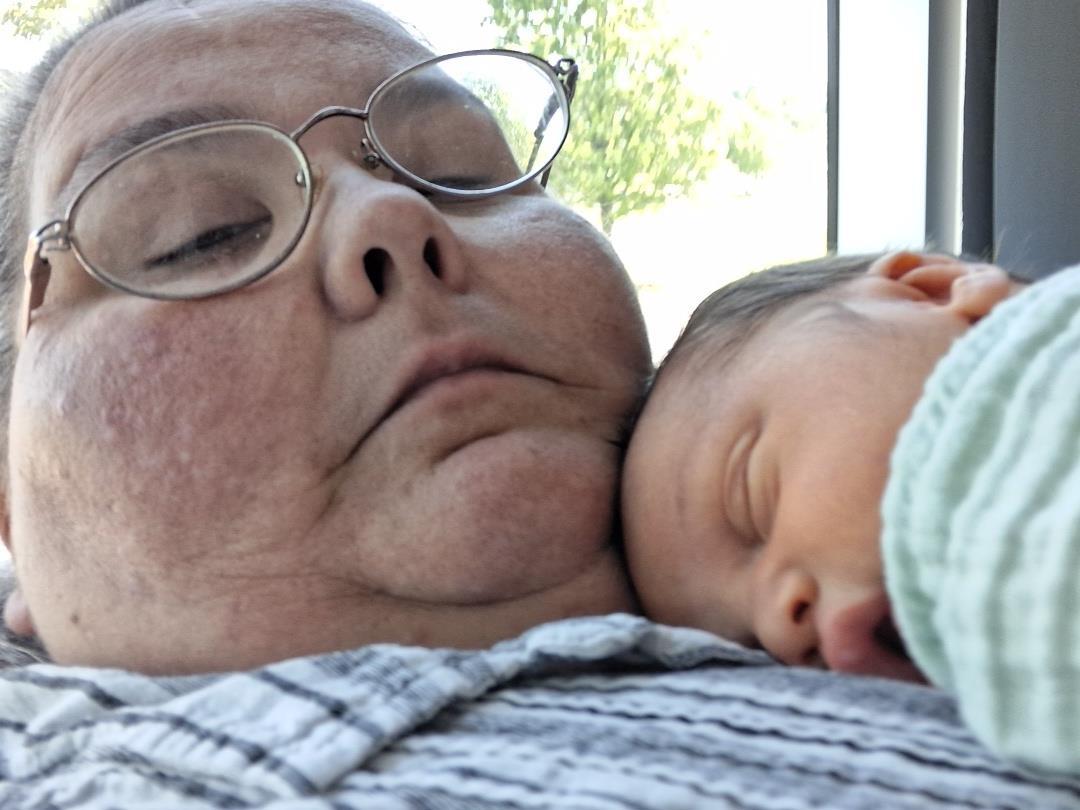 A woman with glasses and a baby sleeping