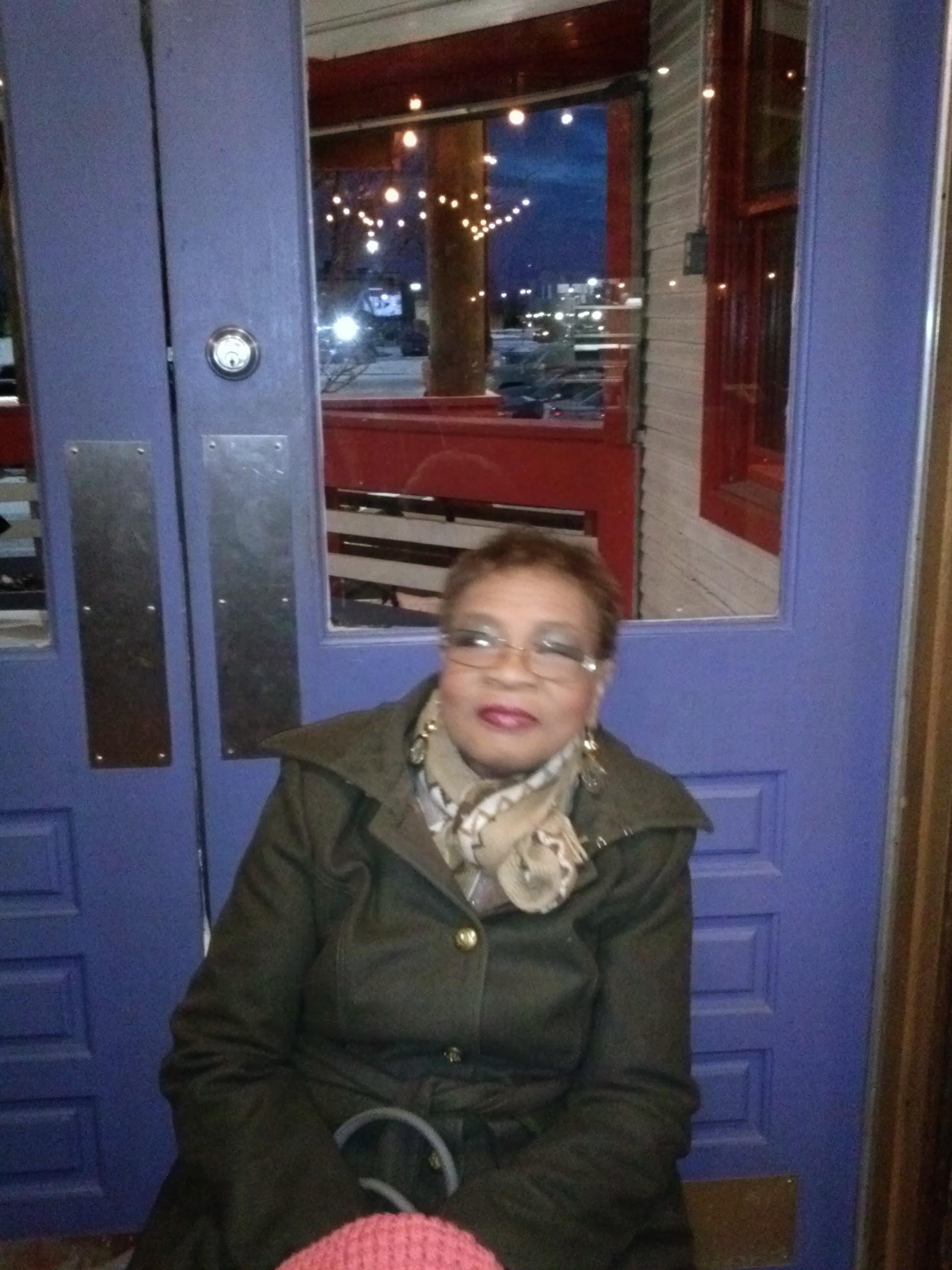 A woman sitting in front of a blue door