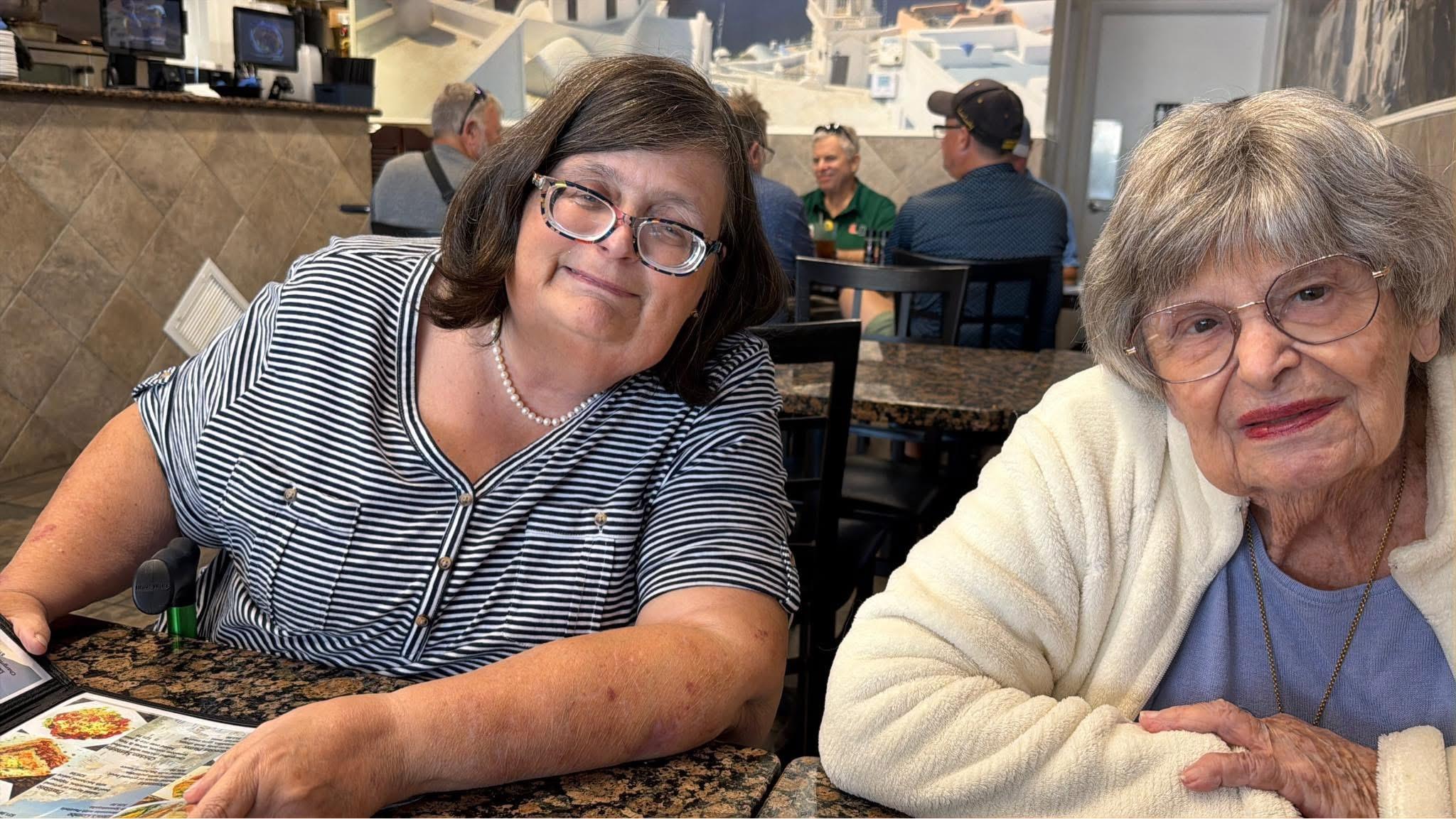 A woman sitting at a table with another woman smiling