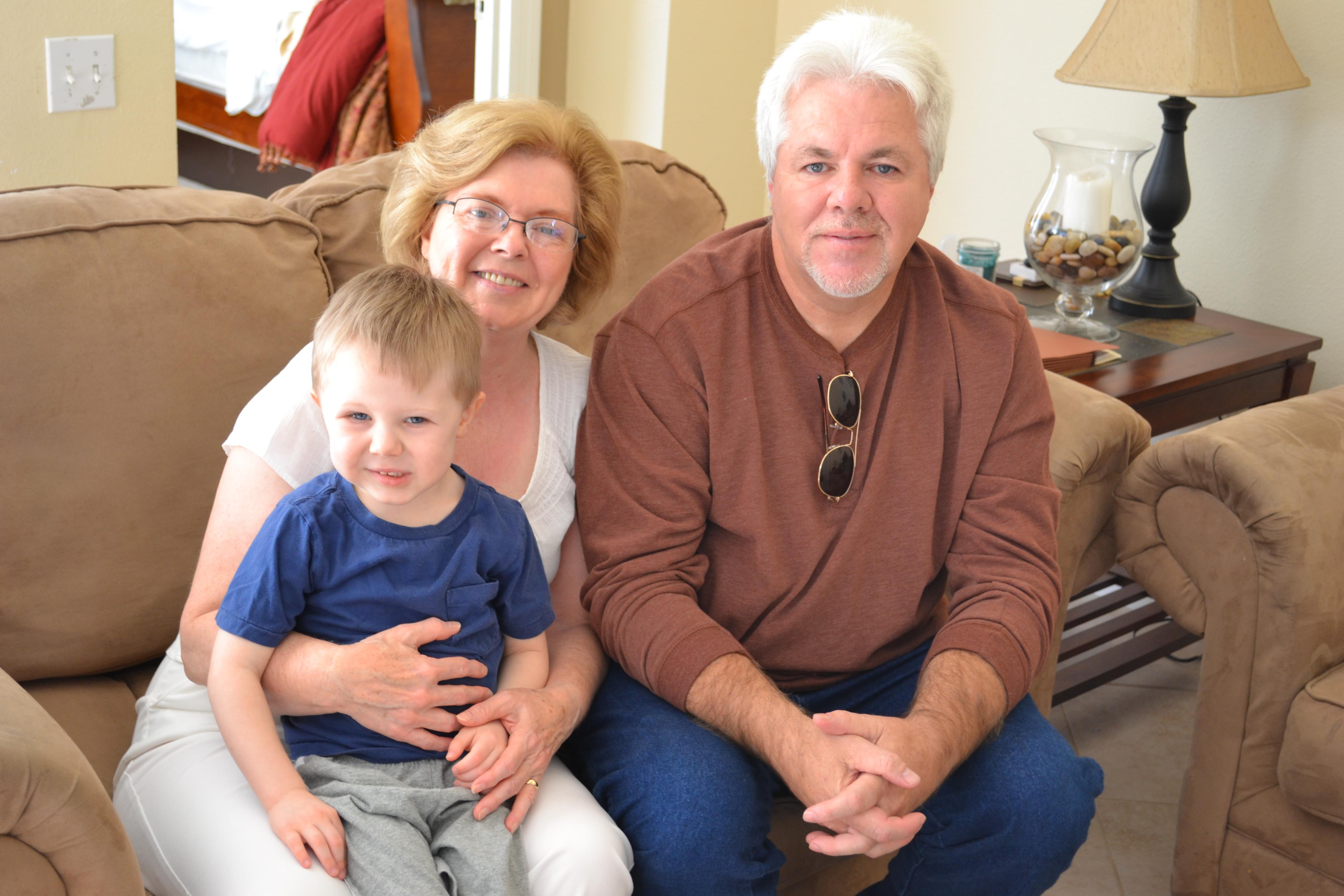A man and woman sitting on a couch with a child