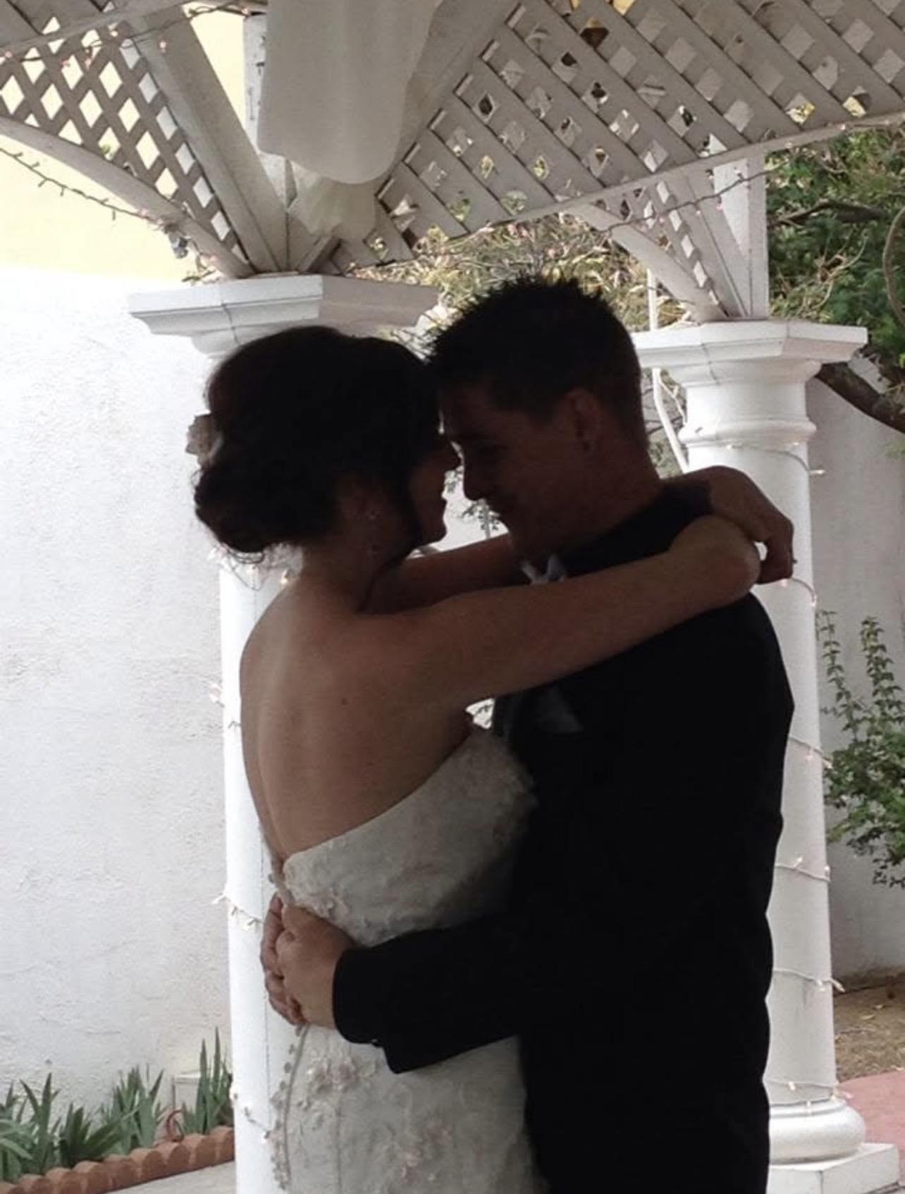 A man and woman hugging under a white arbor