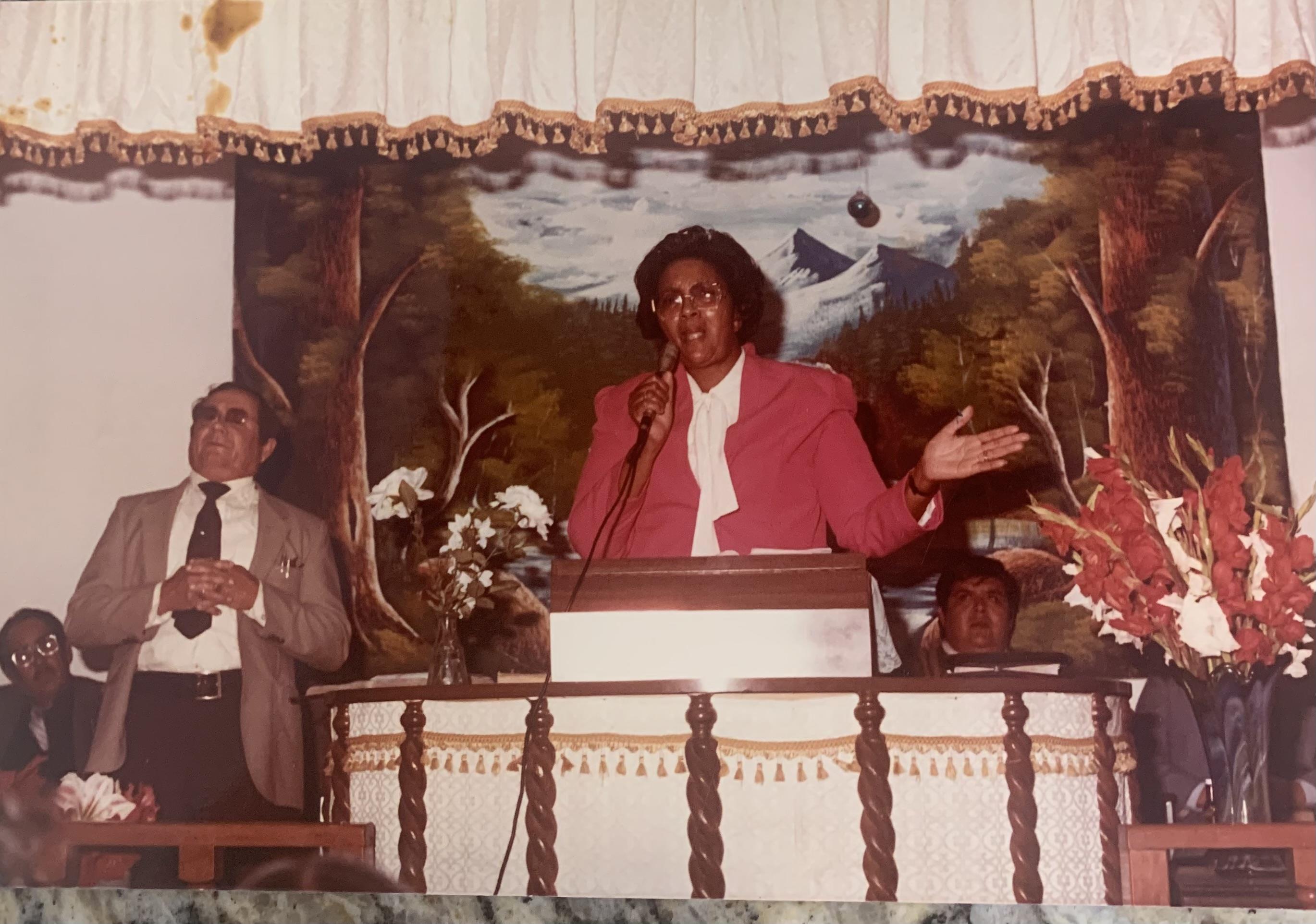 A man in a red suit speaking into a microphone