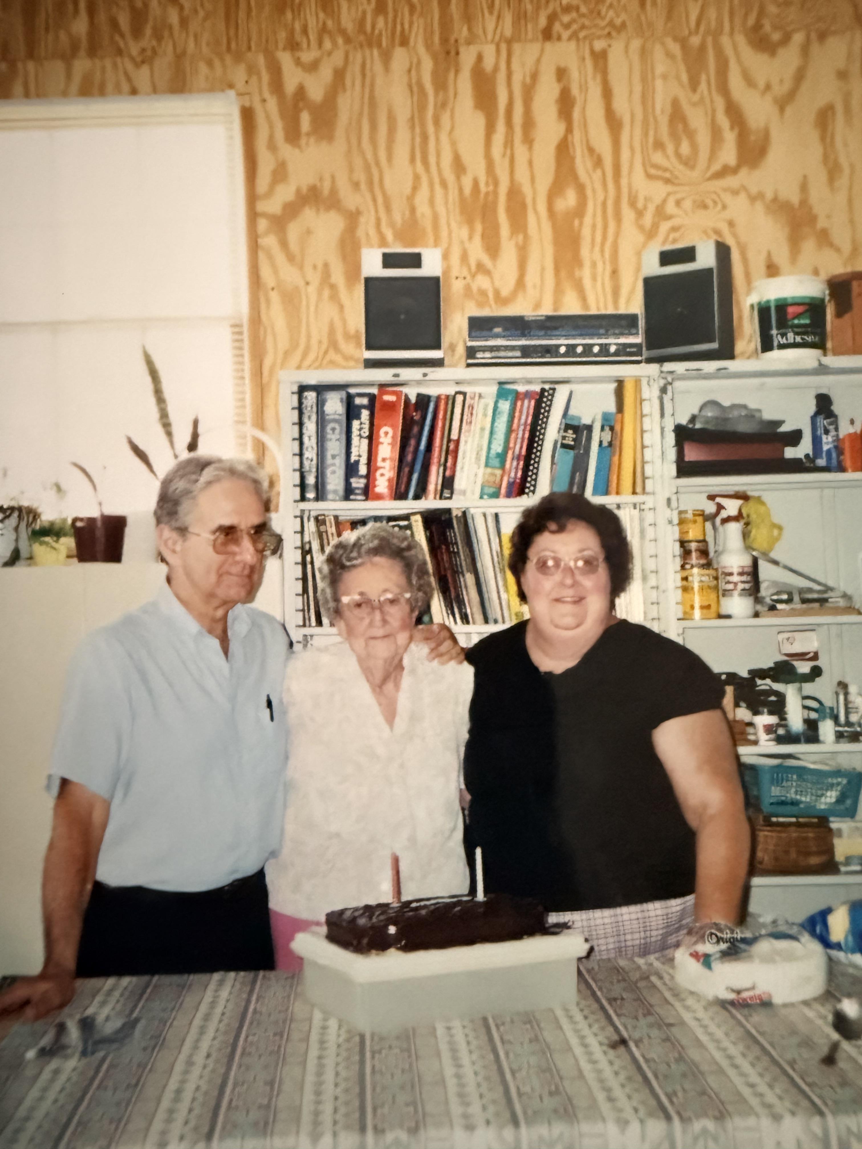 A group of people standing in front of a table with a cake