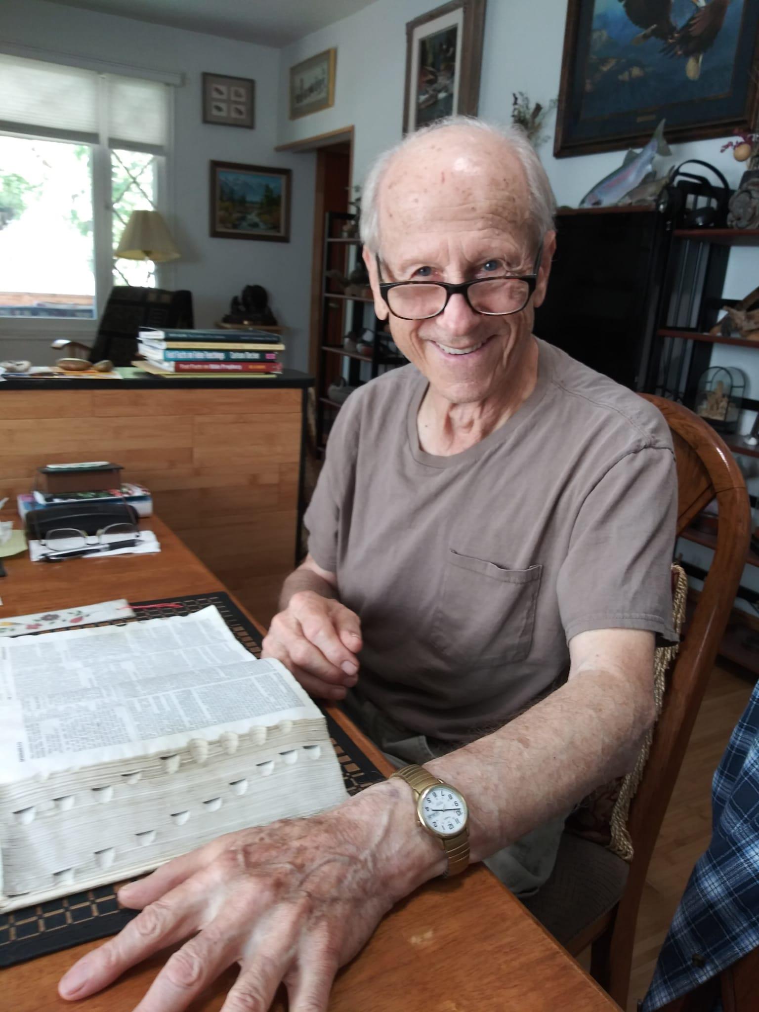 A man sitting at a table with a stack of newspapers
