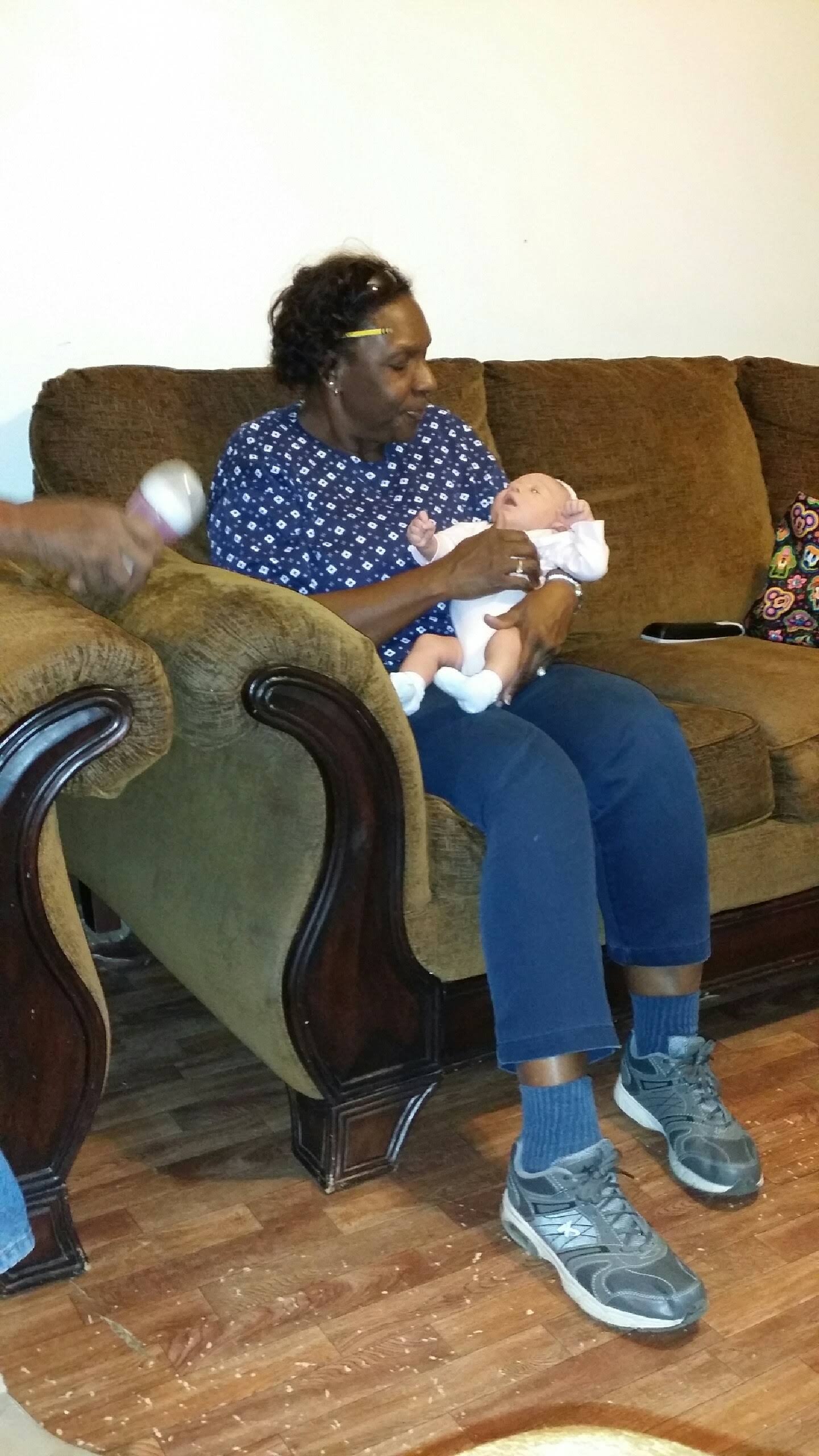 A woman sitting on a couch holding a baby
