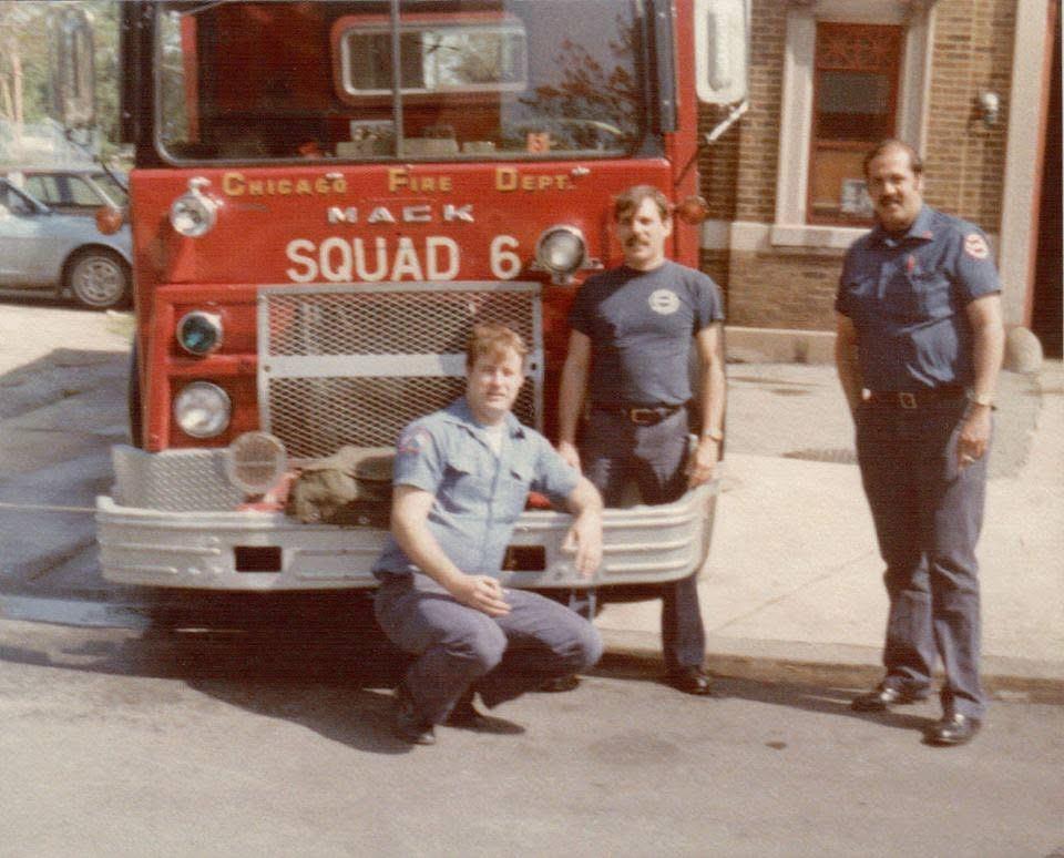 A group of men posing in front of a fire truck