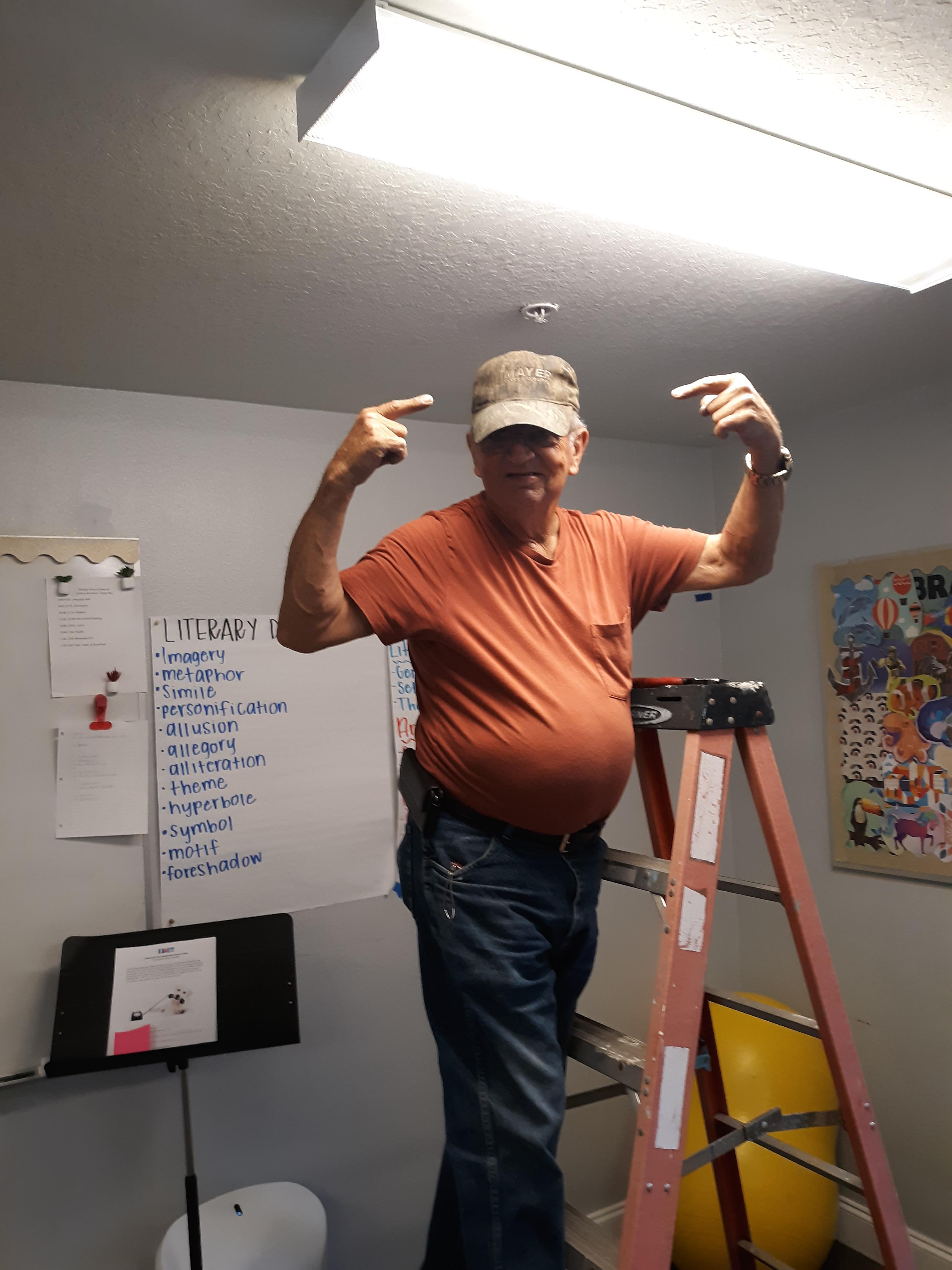 A man on a ladder pointing at his hand
