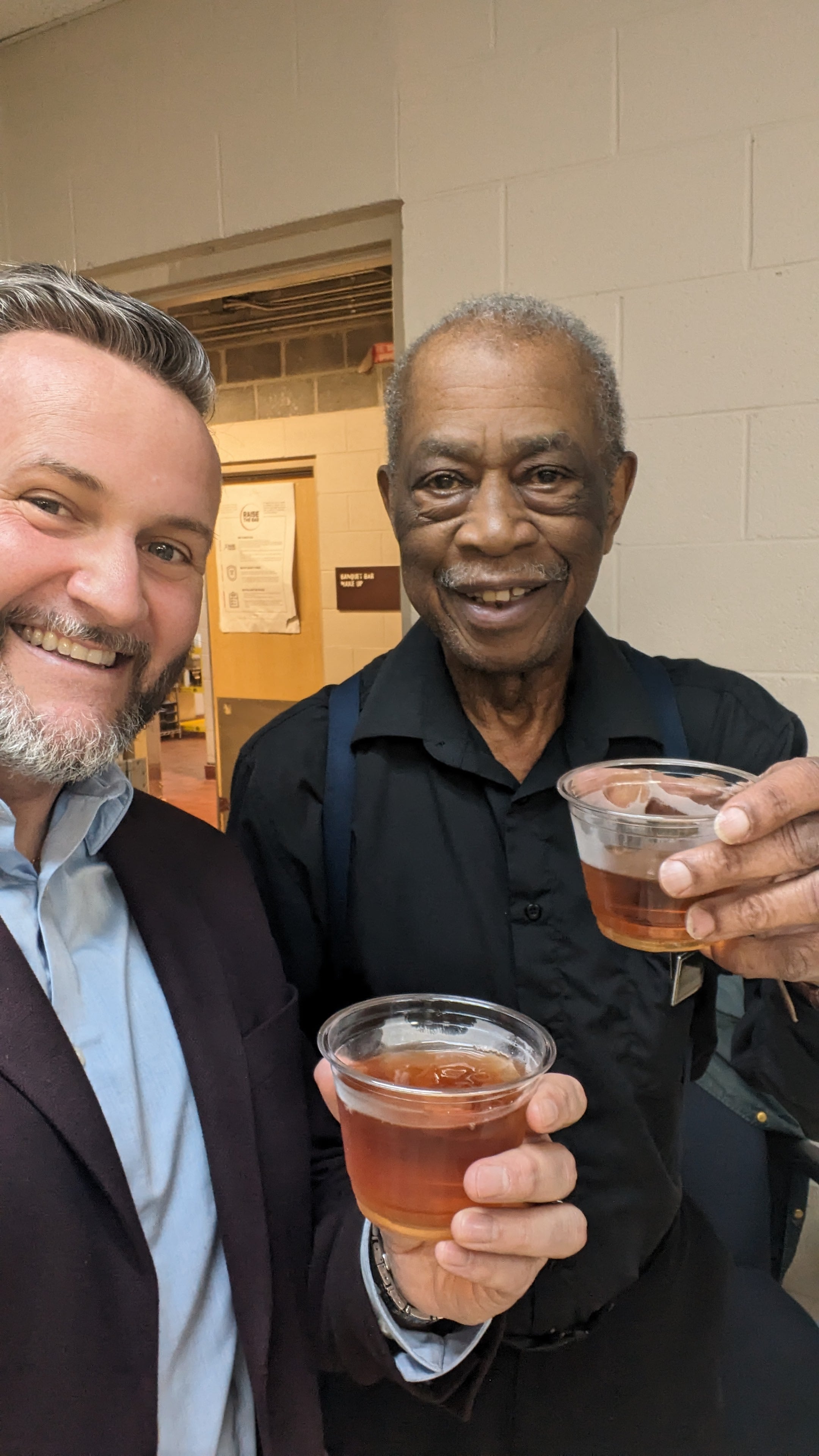Two men holding cups of liquid