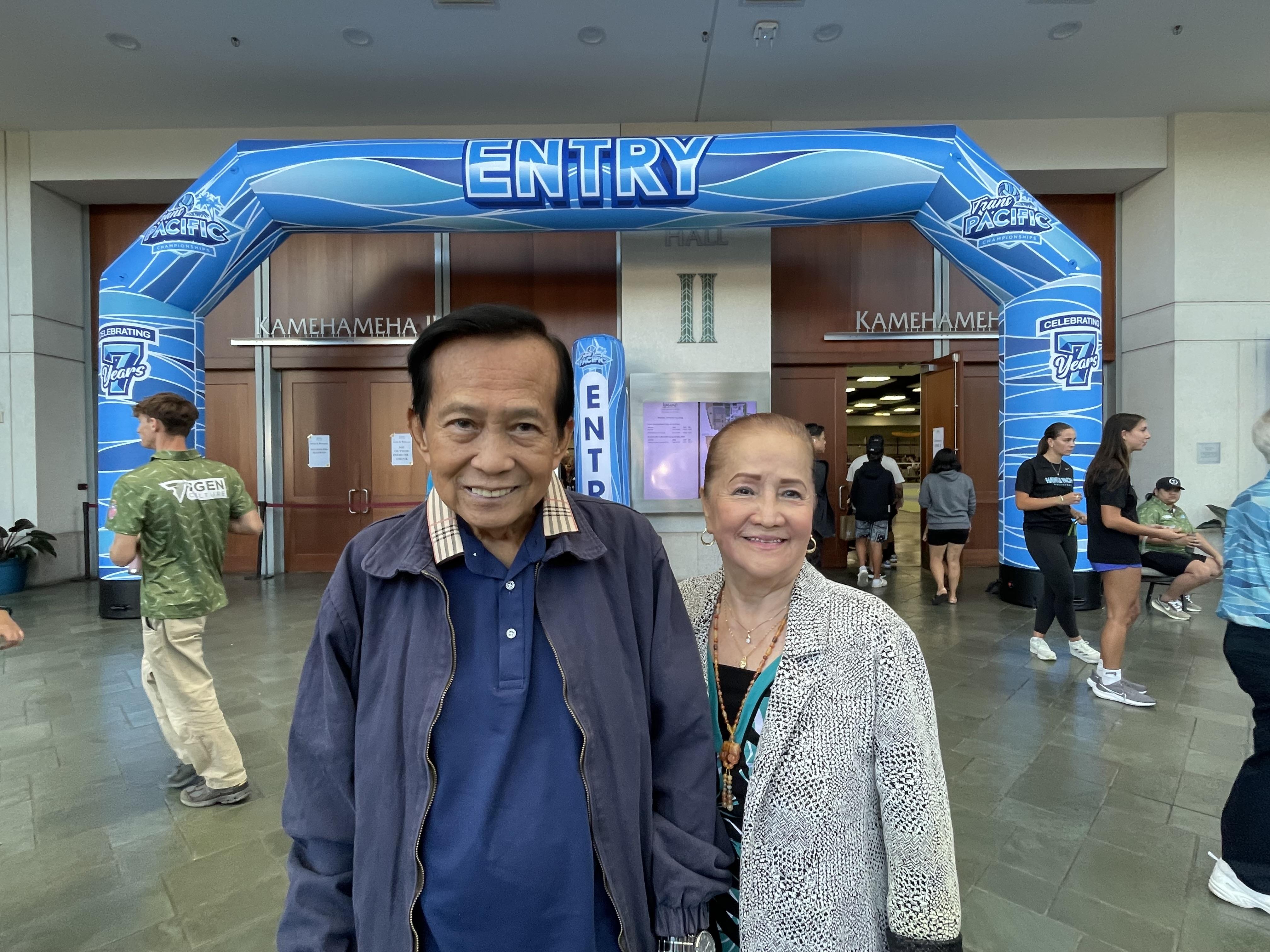A man and woman standing in front of a blue archway