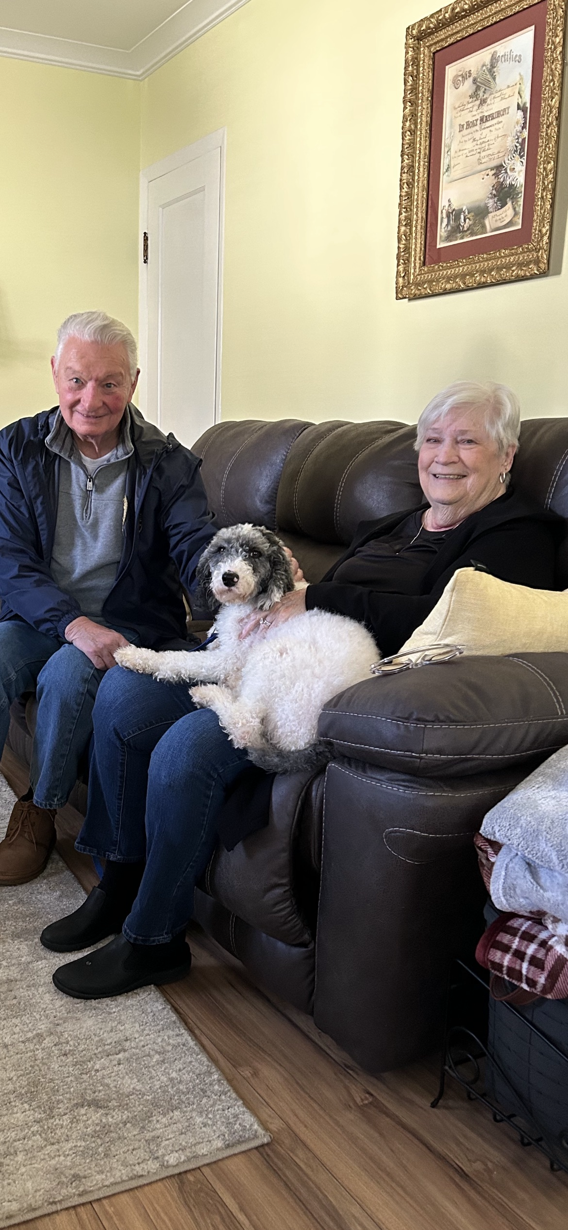 A man and woman sitting on a couch with a dog