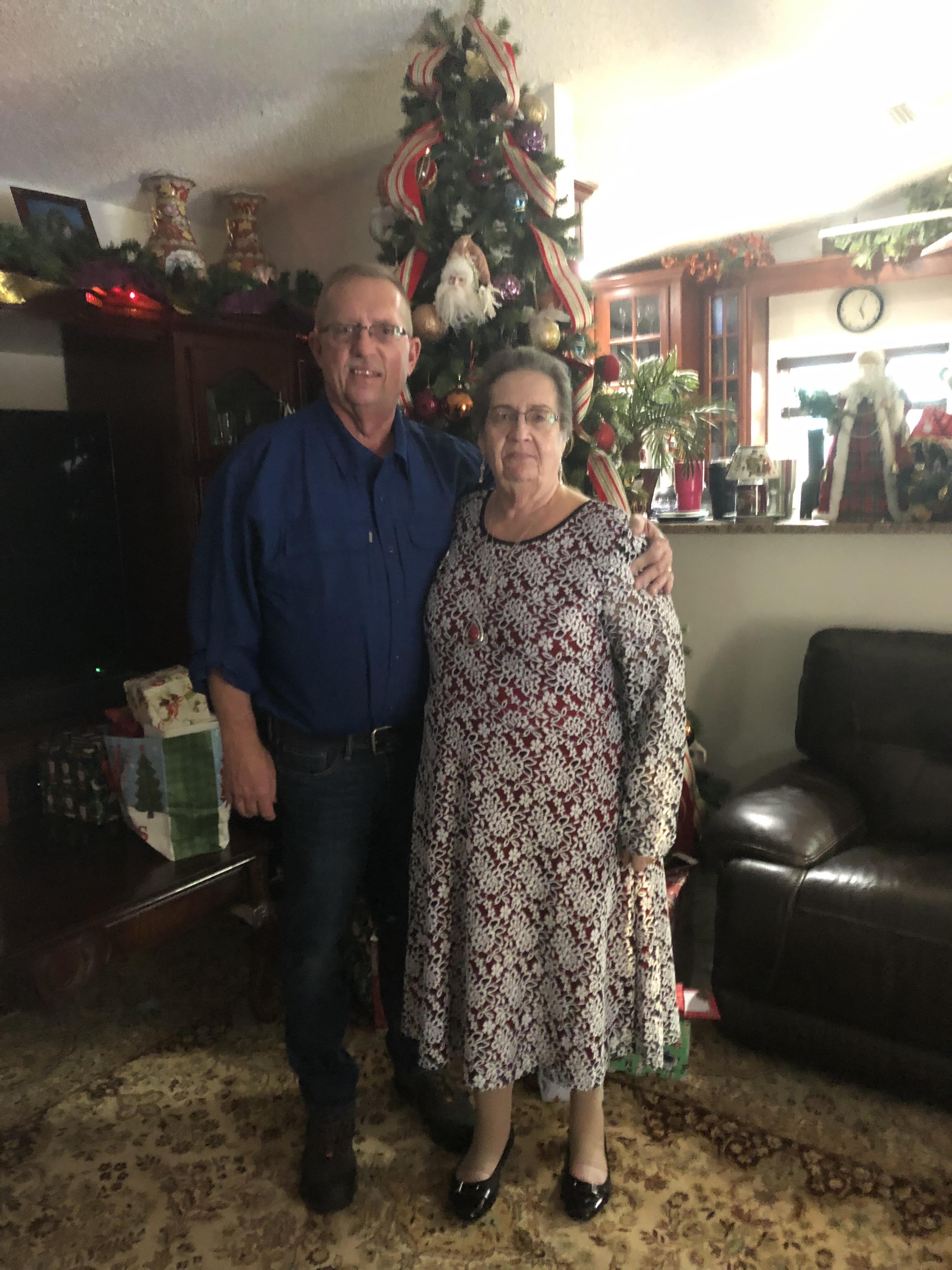 A man and woman standing in front of a christmas tree