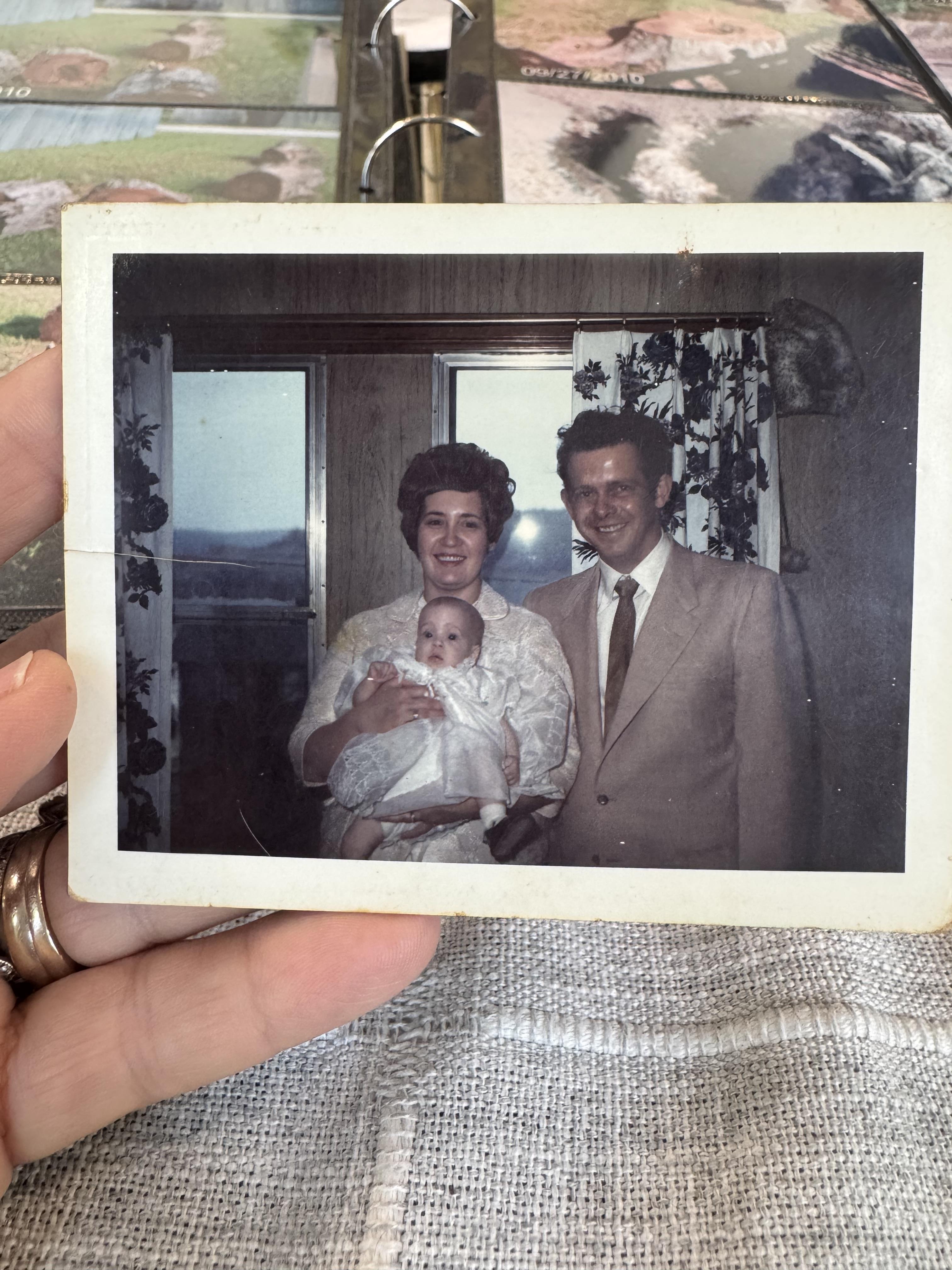 A hand holding a photo of a family