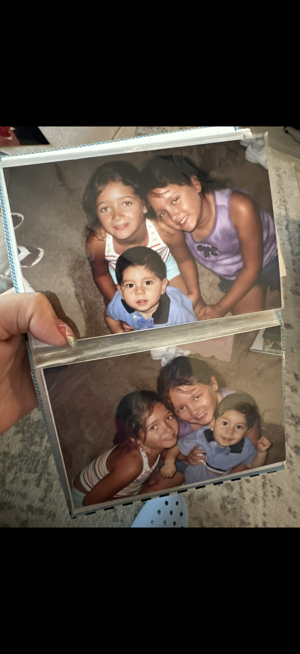 A hand holding a photo of a group of children