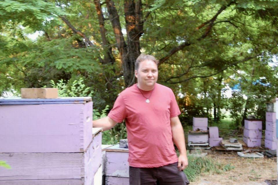 A man standing next to a stack of beehives