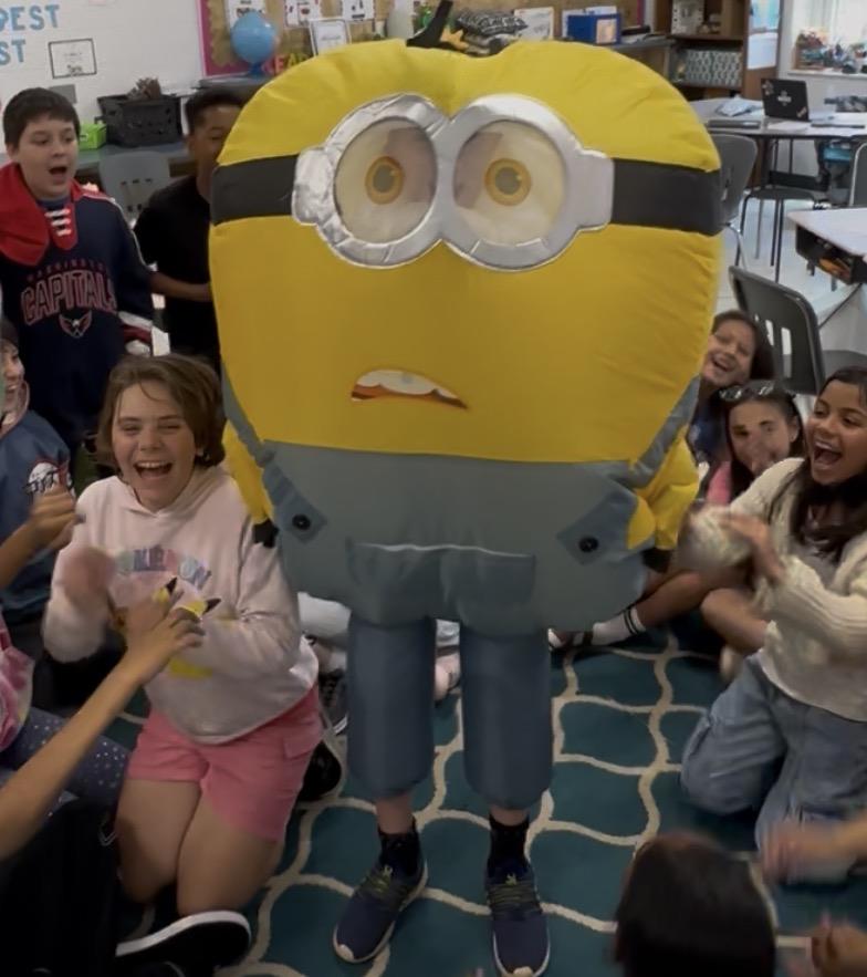 A group of kids in a room with a yellow and grey mascot
