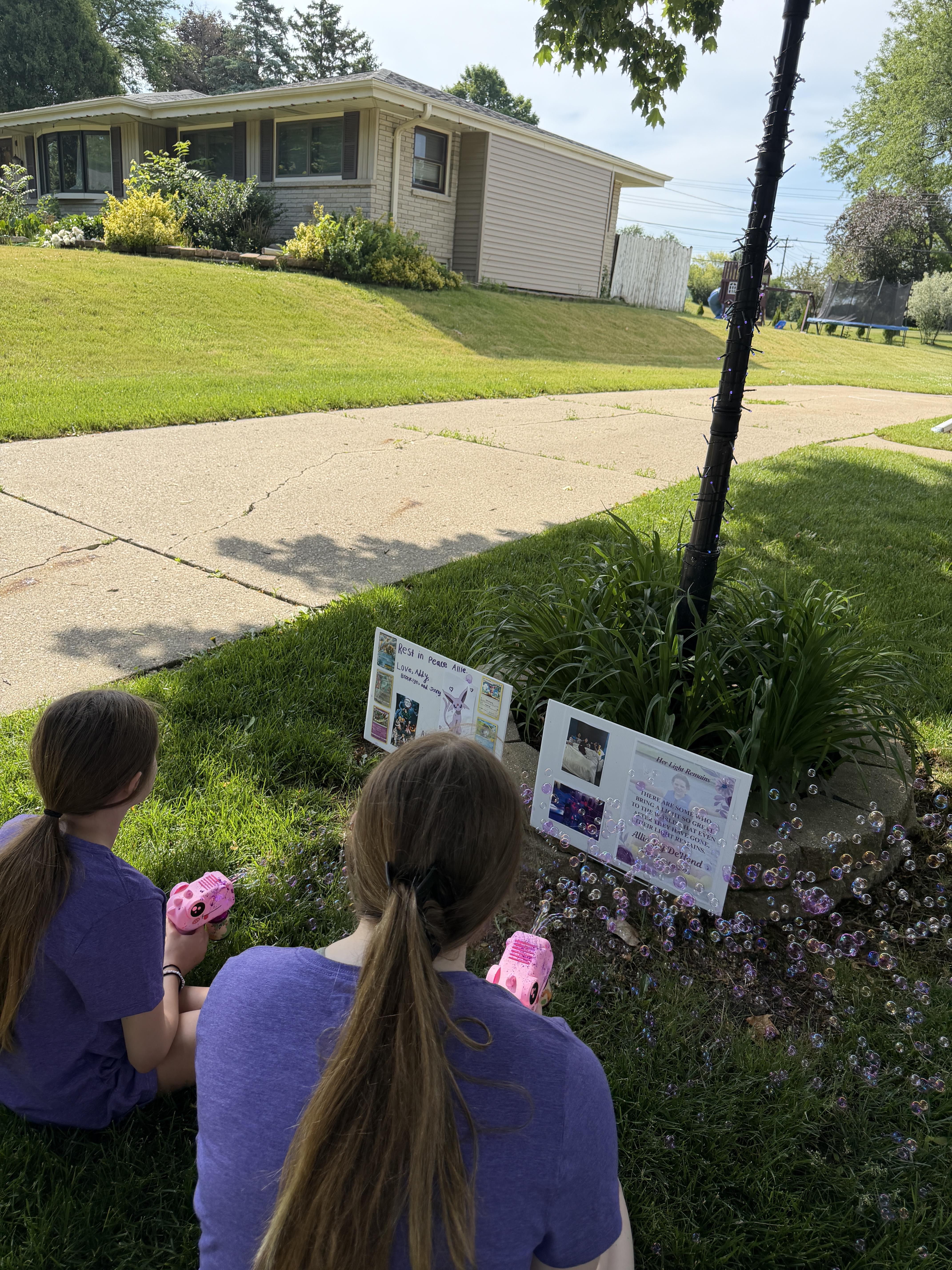Two girls sitting in the grass looking at a sign