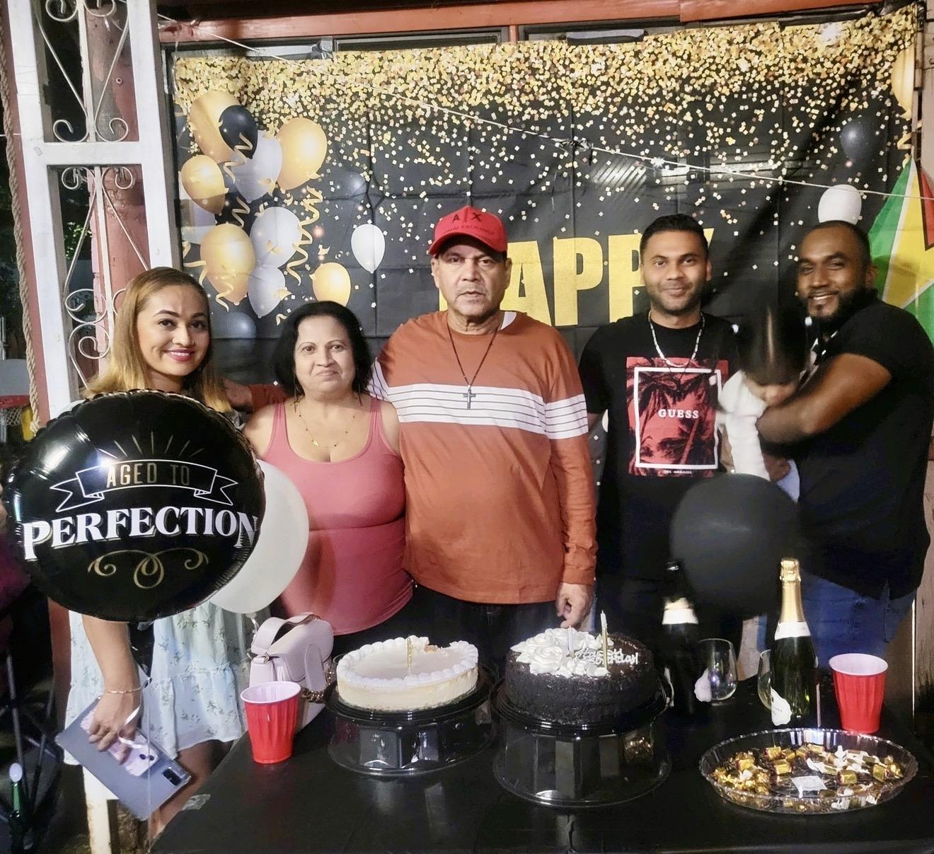 A group of people standing in front of a table with food and balloons