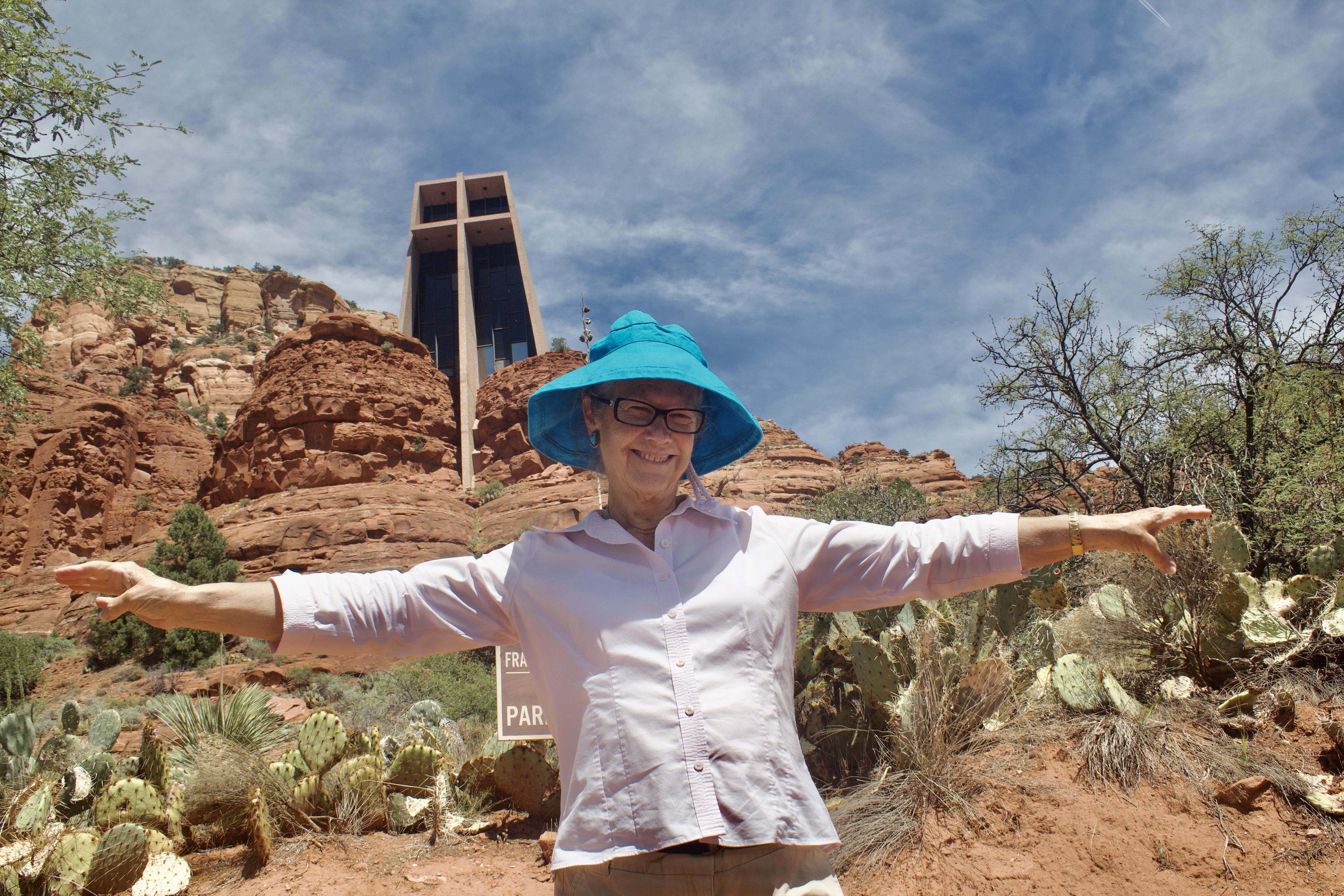 A woman wearing a blue hat with her arms out in front of a cross