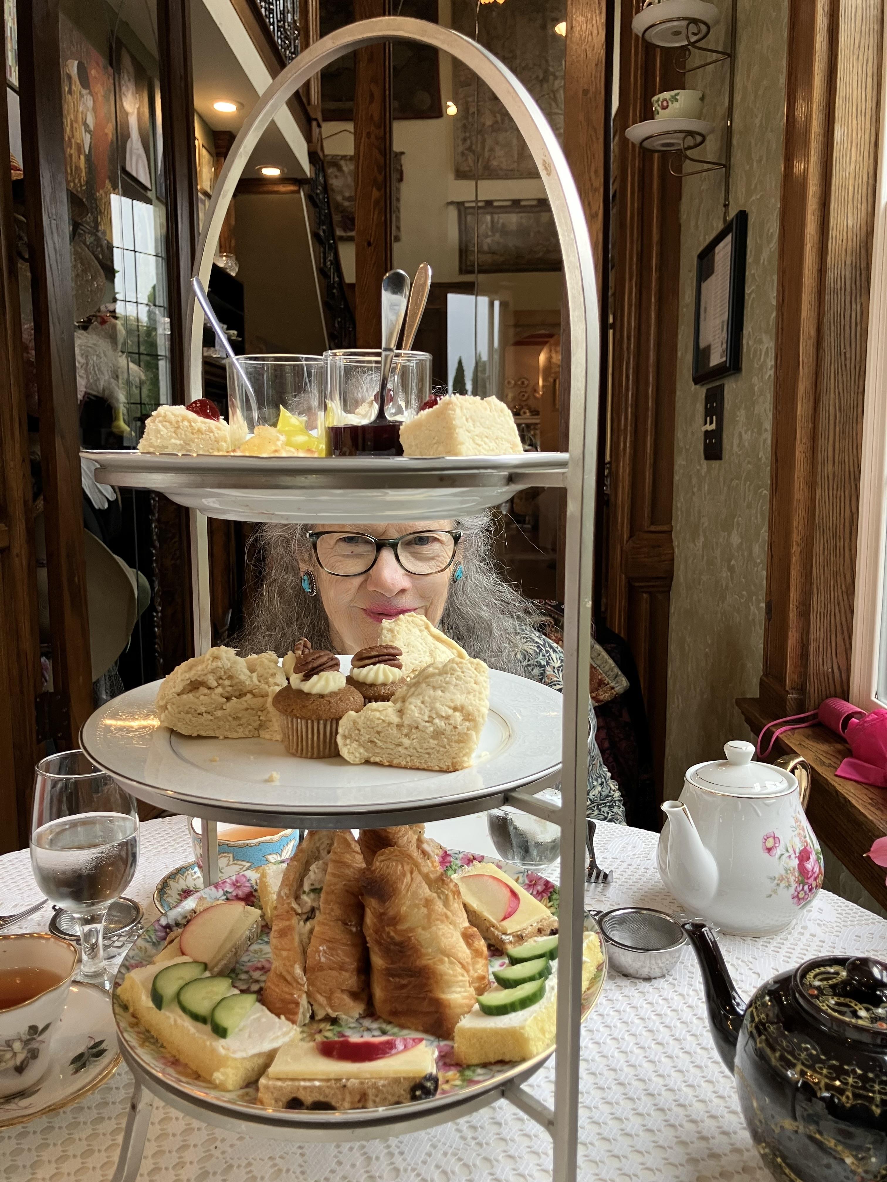 A woman sitting at a table with food on a tiered tray