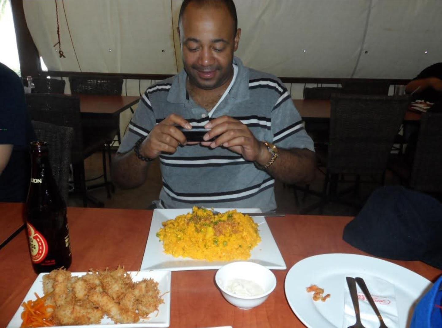 A man sitting at a table with food on his phone