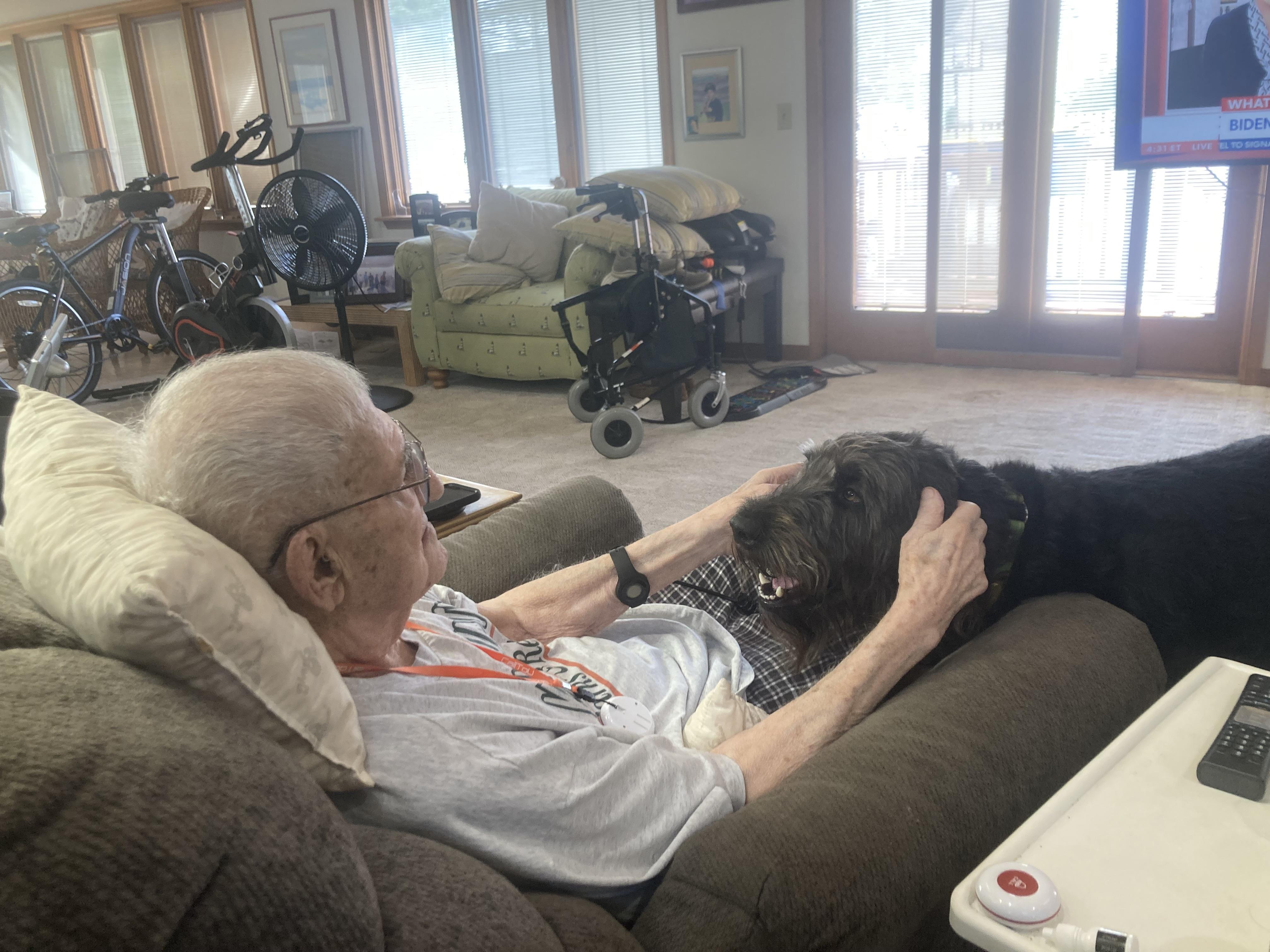 An old man lying on a couch with a dog