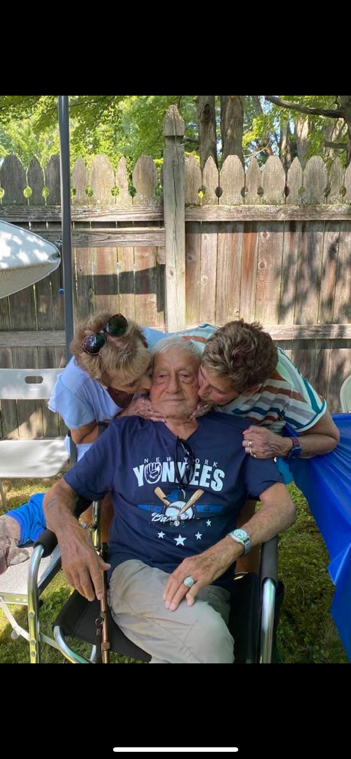 A group of people kissing a man in a wheelchair