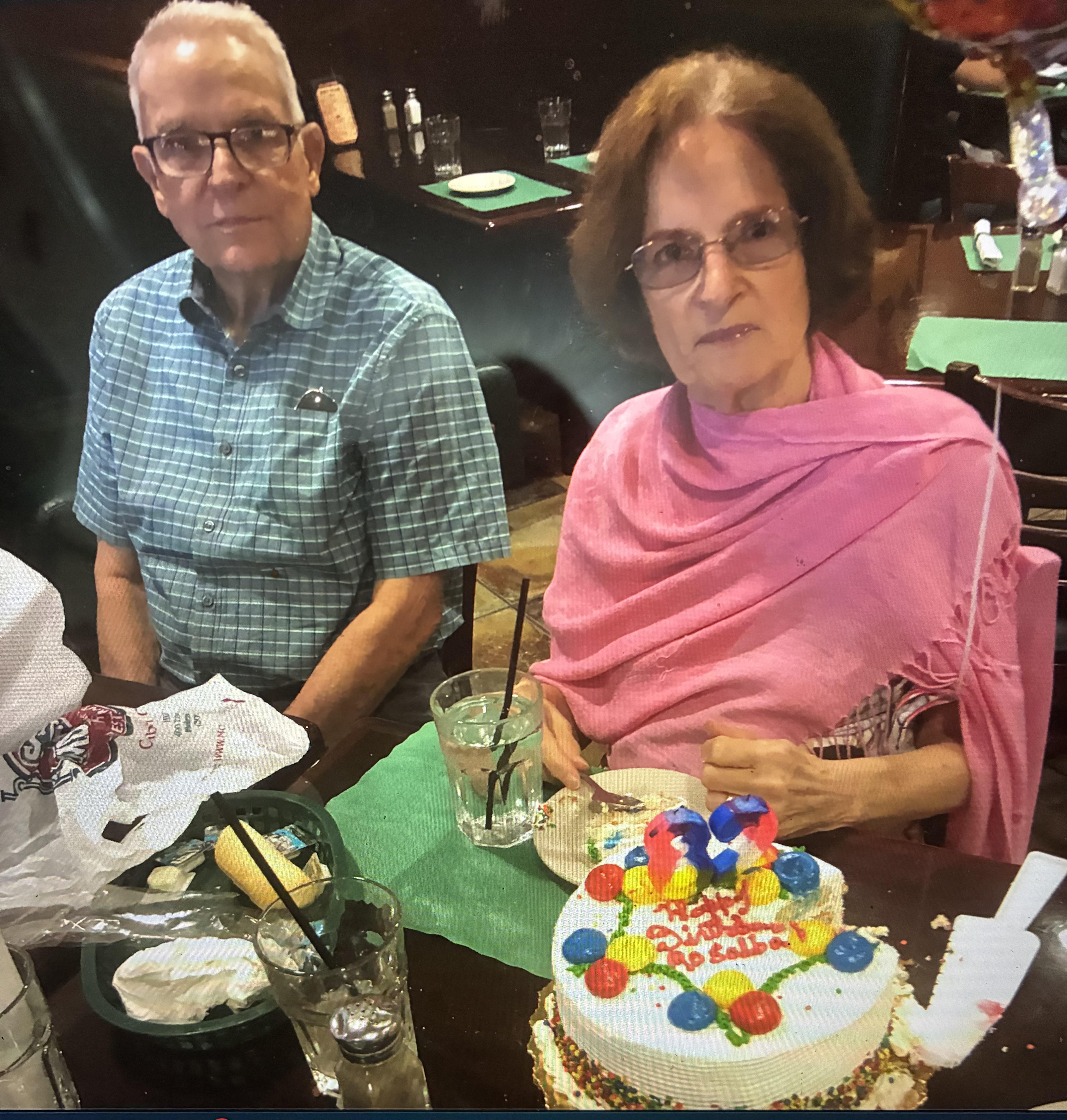 A man and woman sitting at a table with a cake