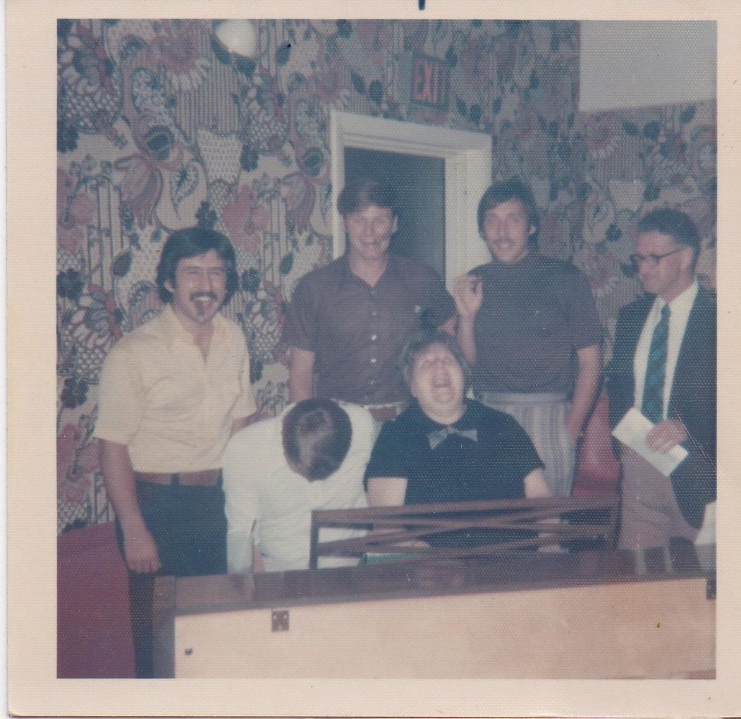 A group of men standing in front of a piano