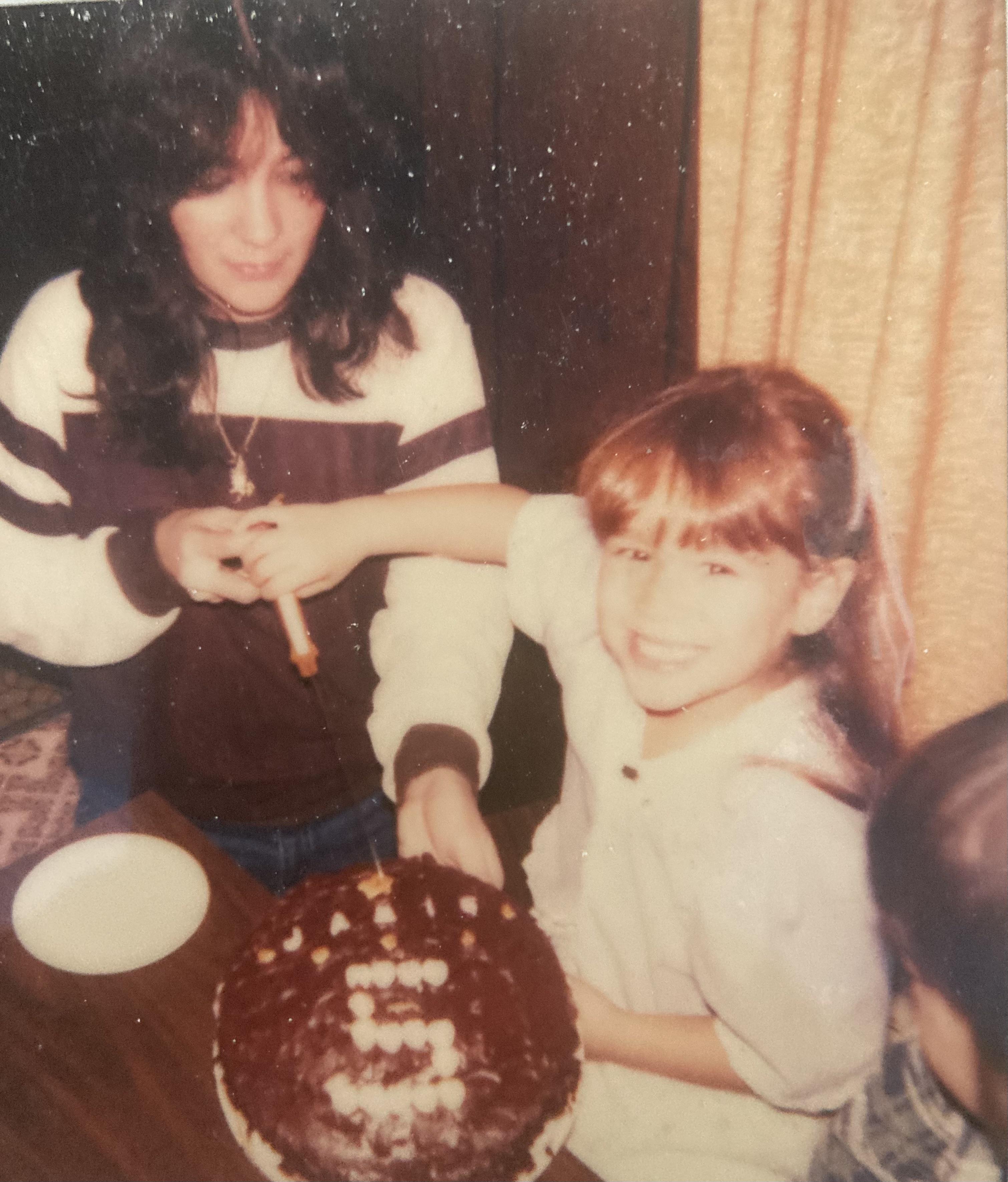 A woman and a girl sitting at a table with a cake