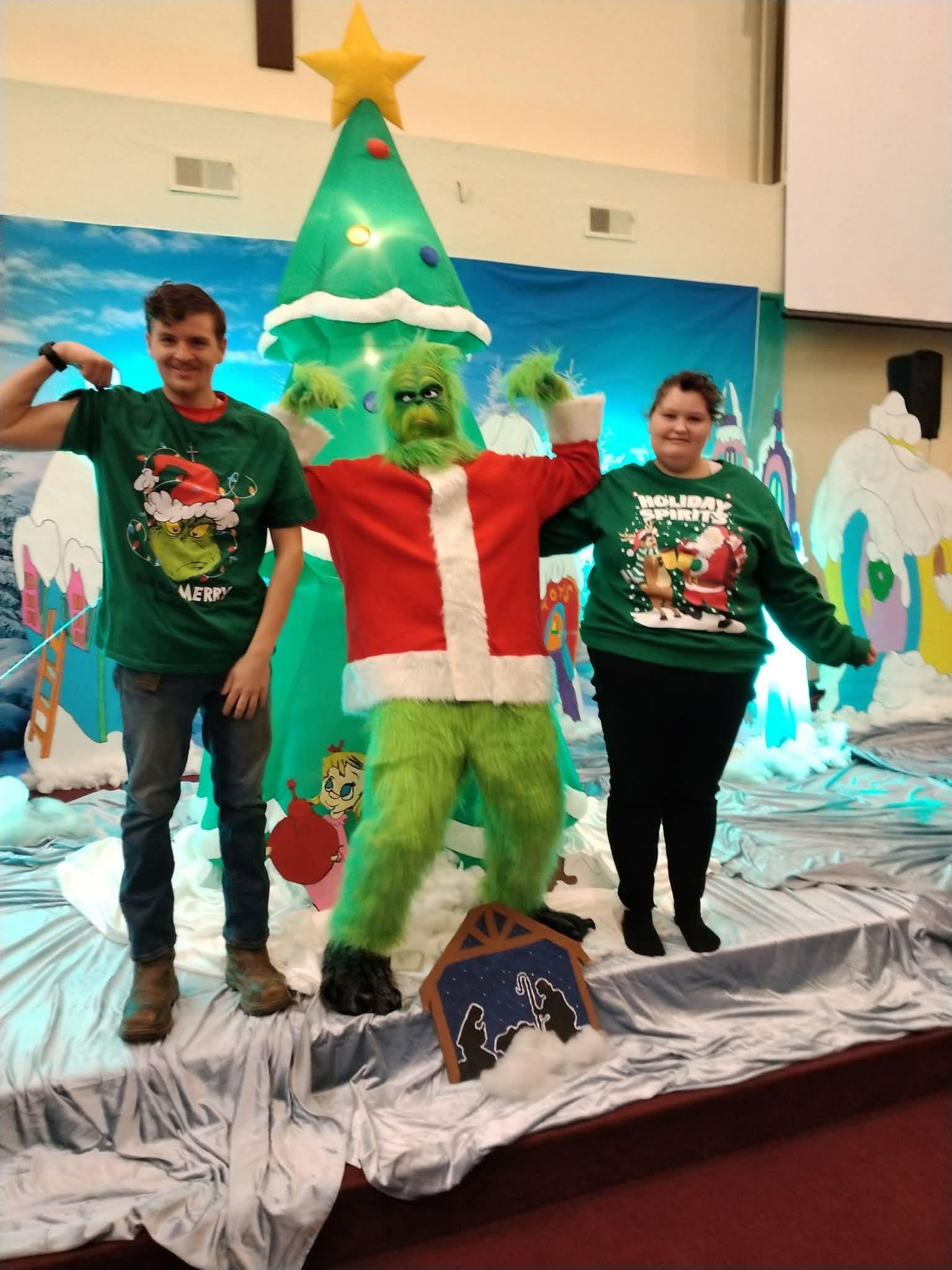 A group of people posing with a green character