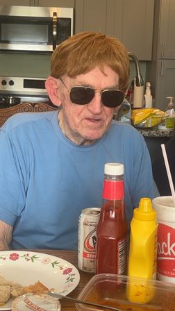 A man wearing sunglasses and sitting at a table with ketchup and mustard