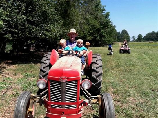 A man and two children riding on a tractor