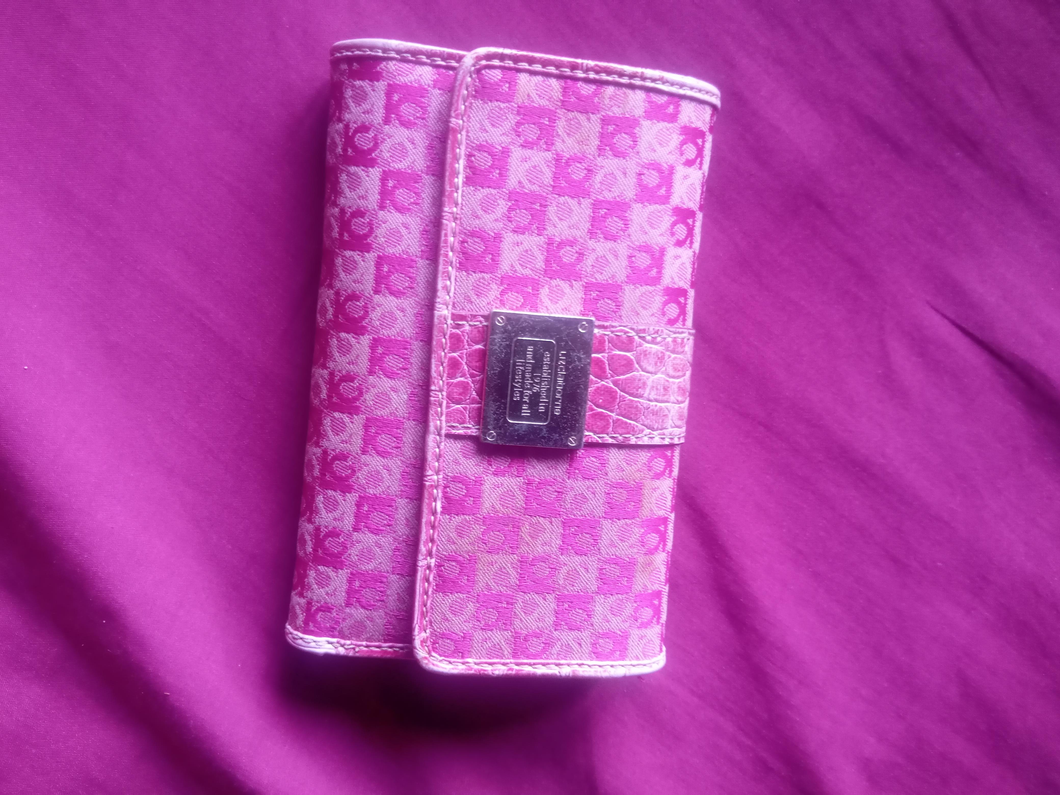 A pink wallet on a purple surface