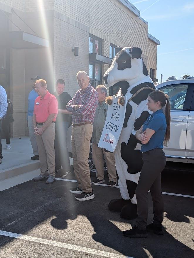 A group of people standing next to a person in a cow garment
