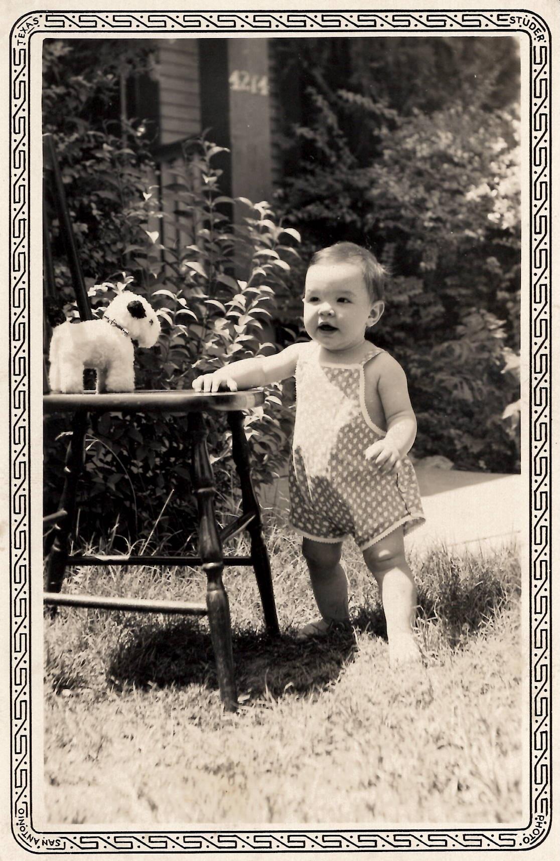 A baby standing next to a chair
