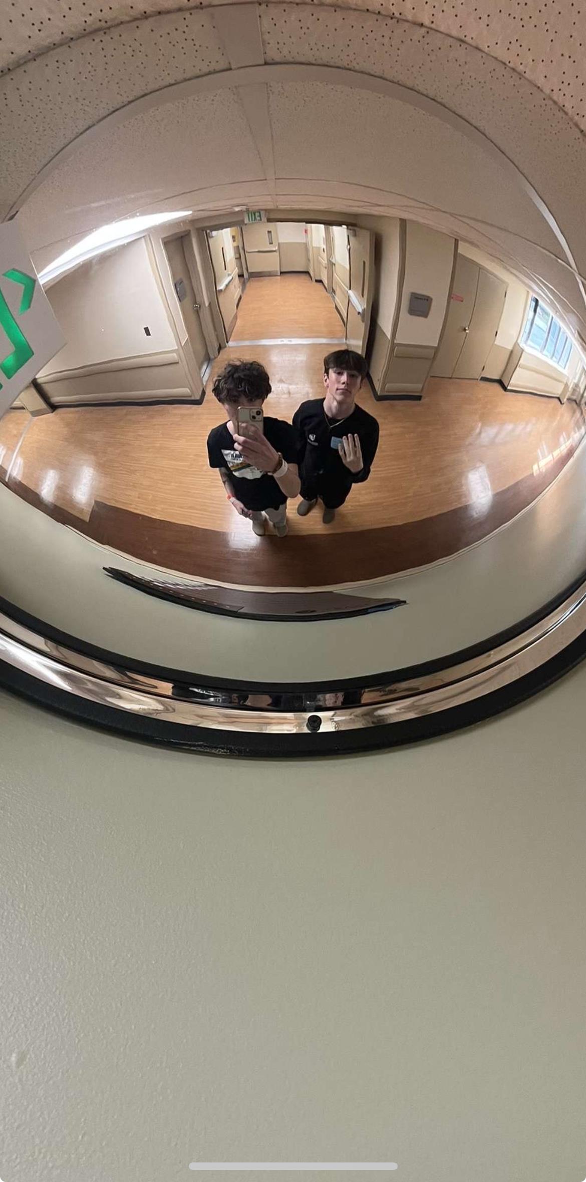Two people standing in a circular mirror