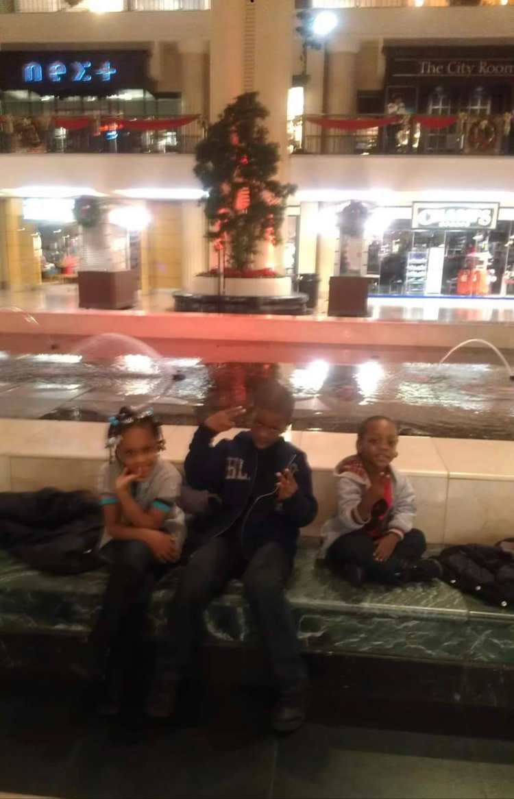 A group of children sitting on a bench in front of a fountain