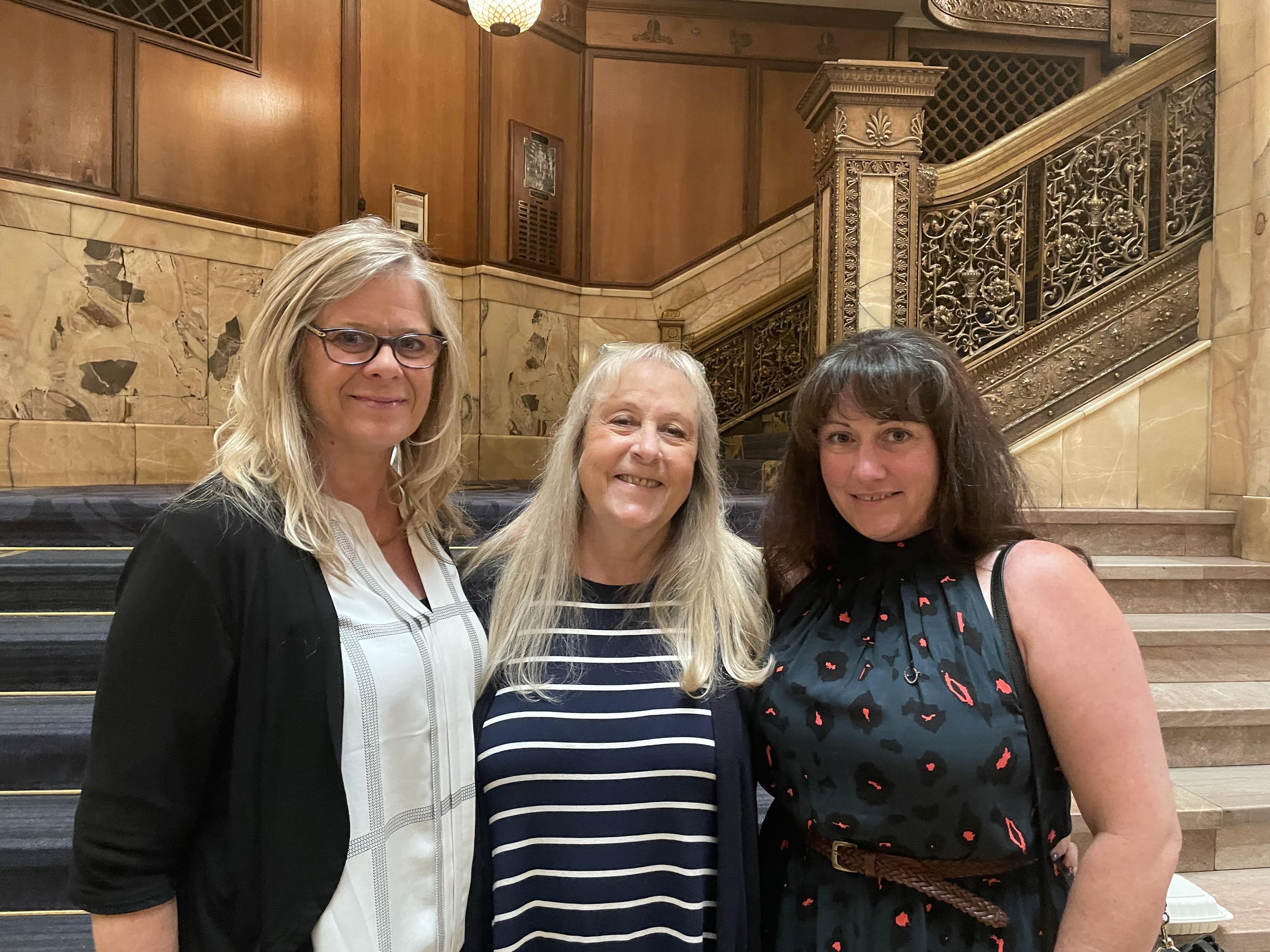 A group of women standing together in a room with stairs