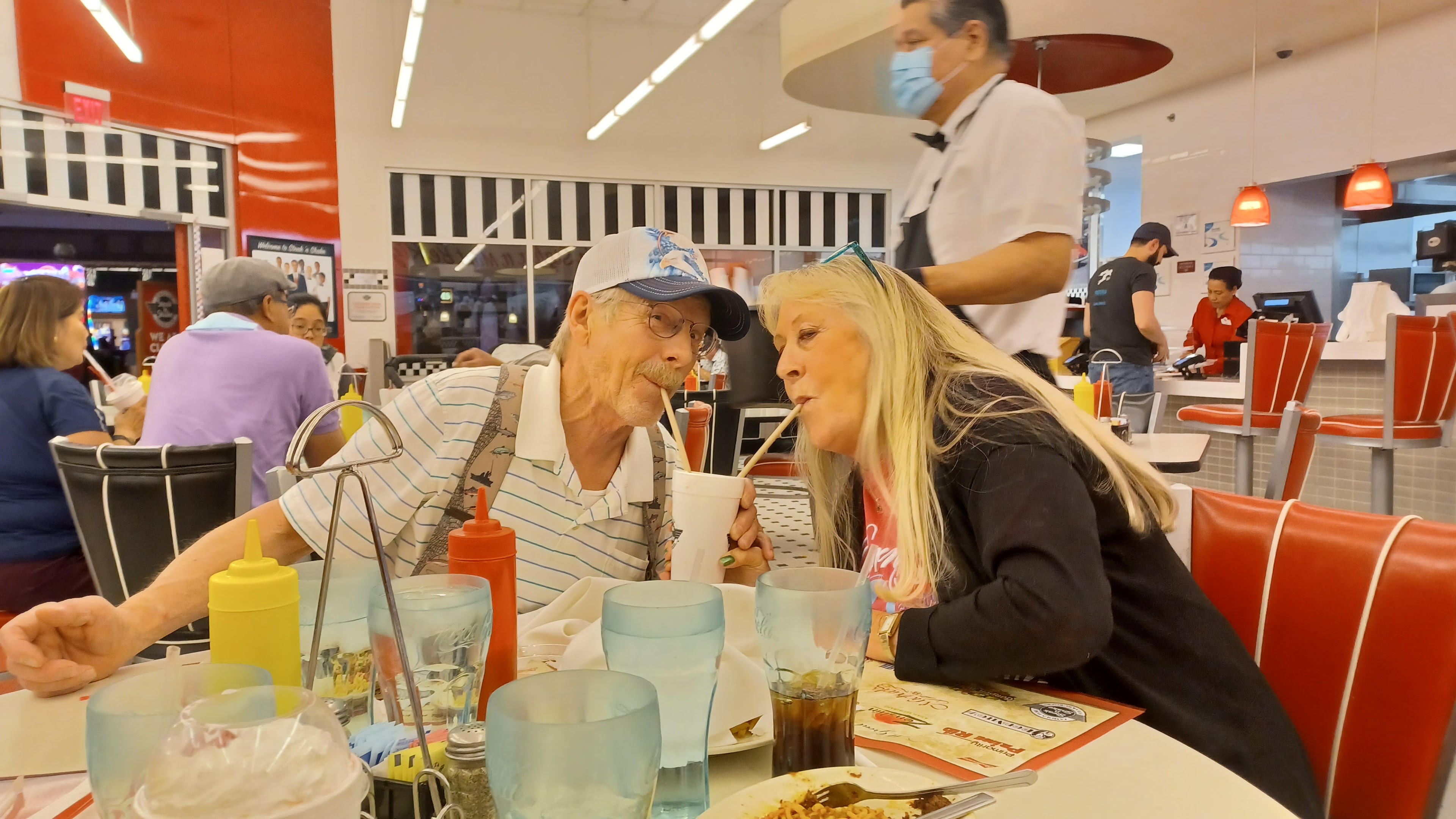 A man and woman sitting at a table with straws