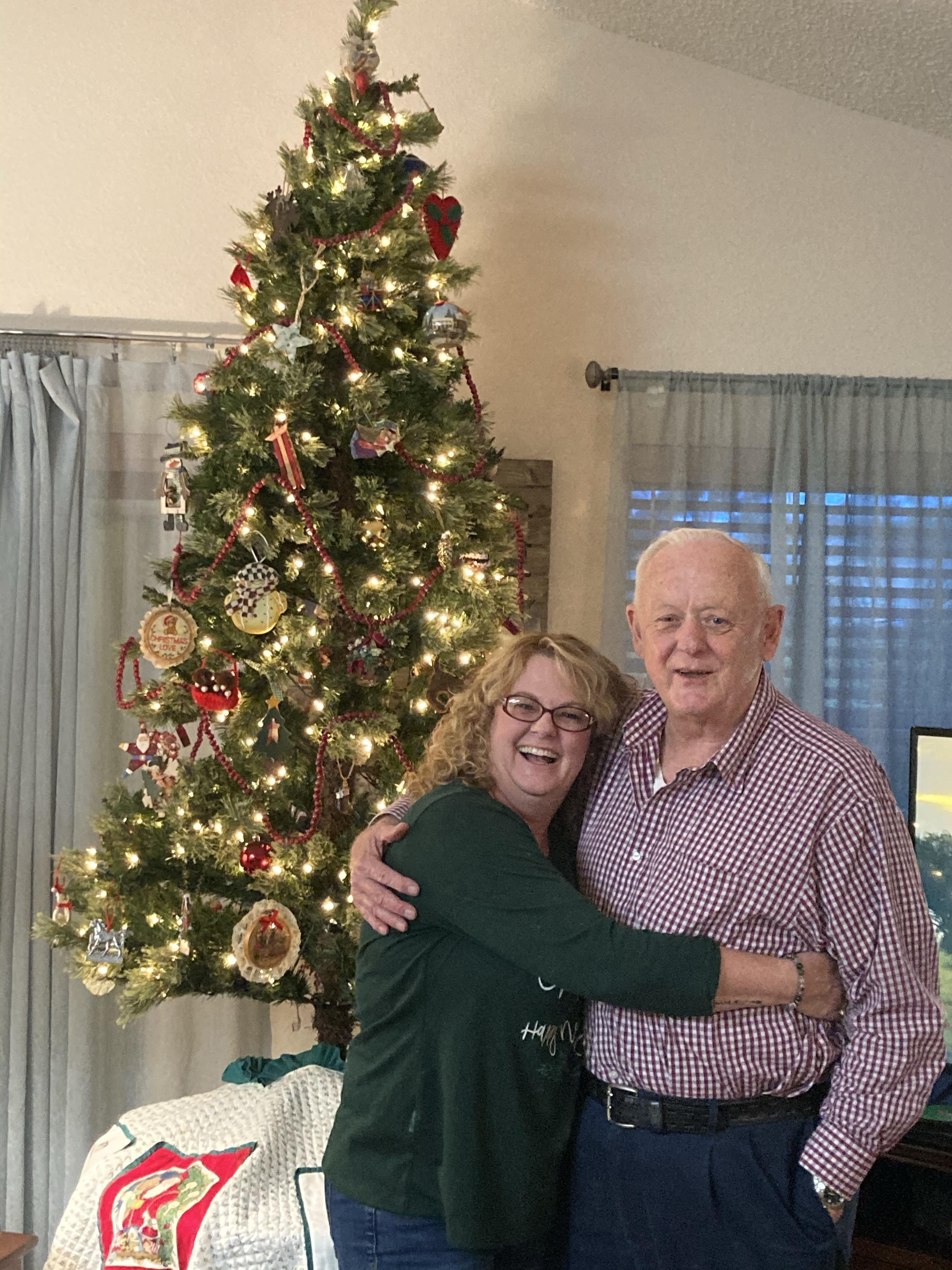 A man and woman standing in front of a christmas tree