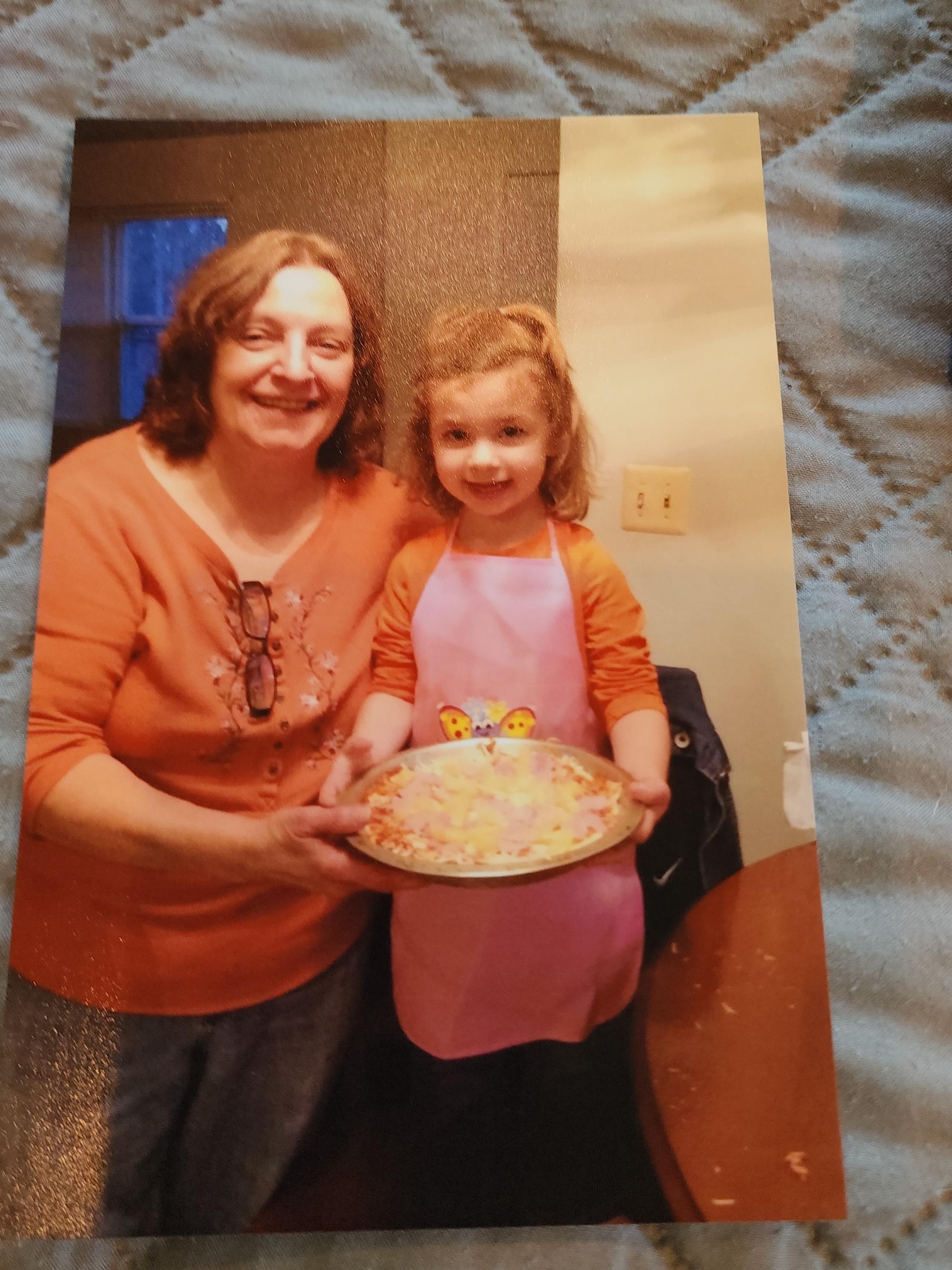 A woman and a girl holding a plate of pizza