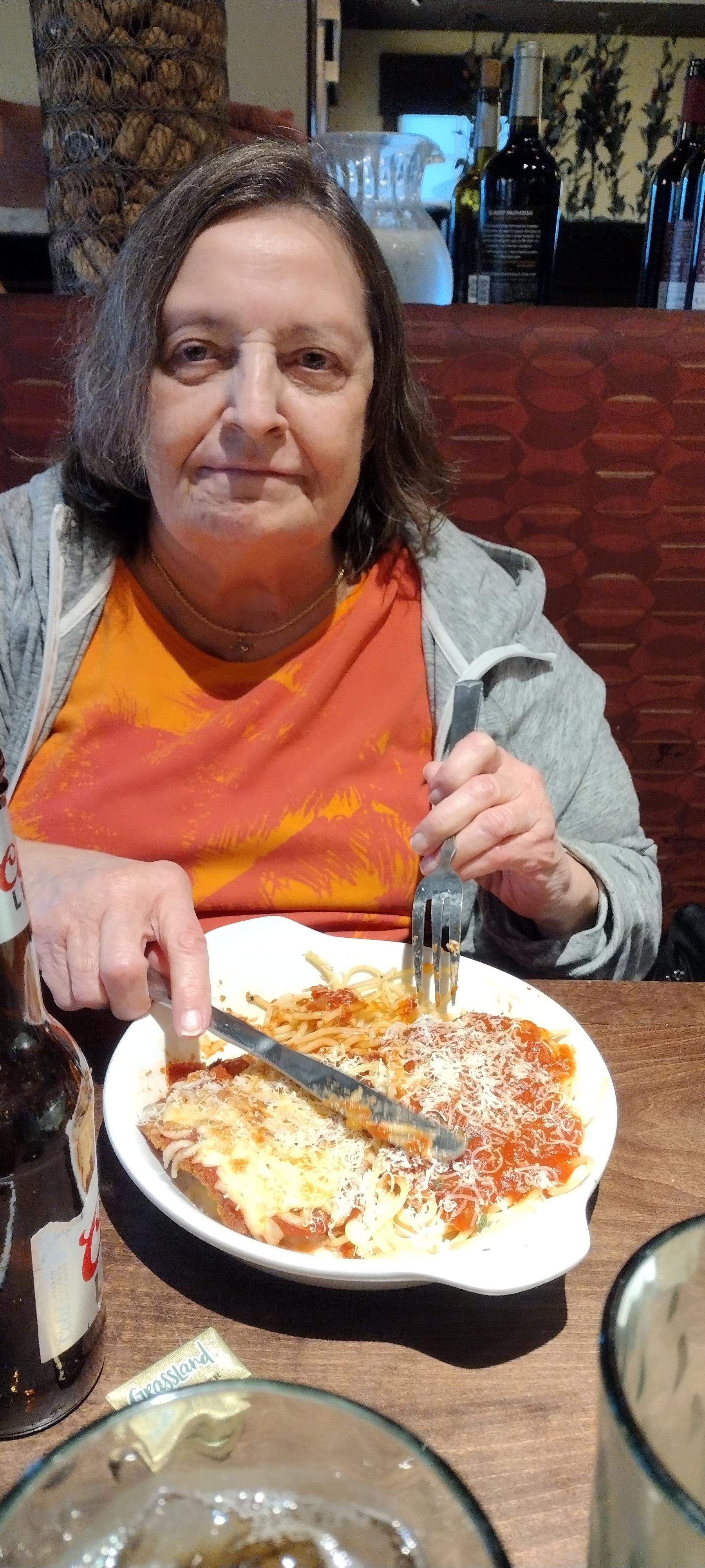 A woman eating pasta with a fork and knife