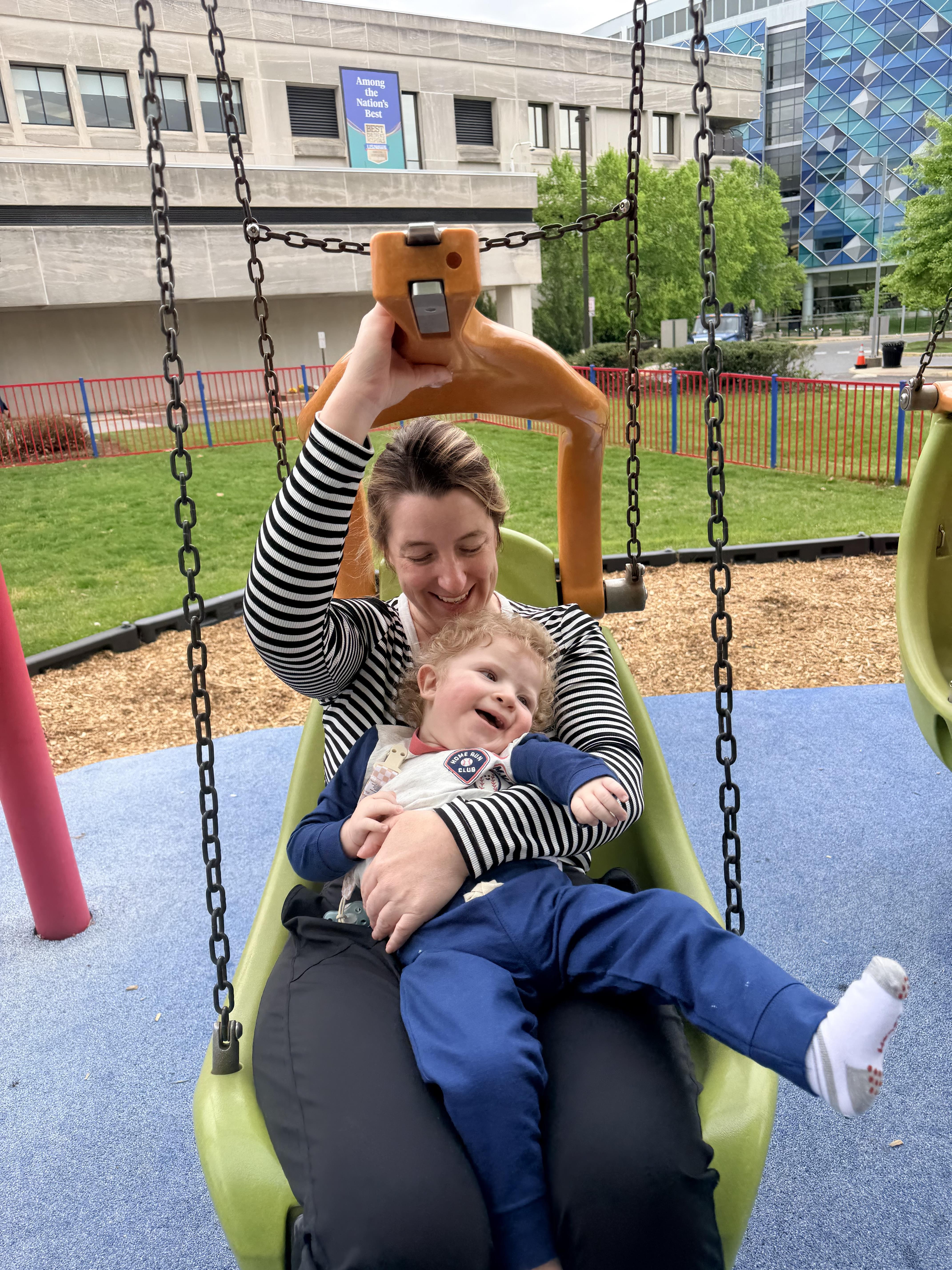 A woman holding a baby on a swing