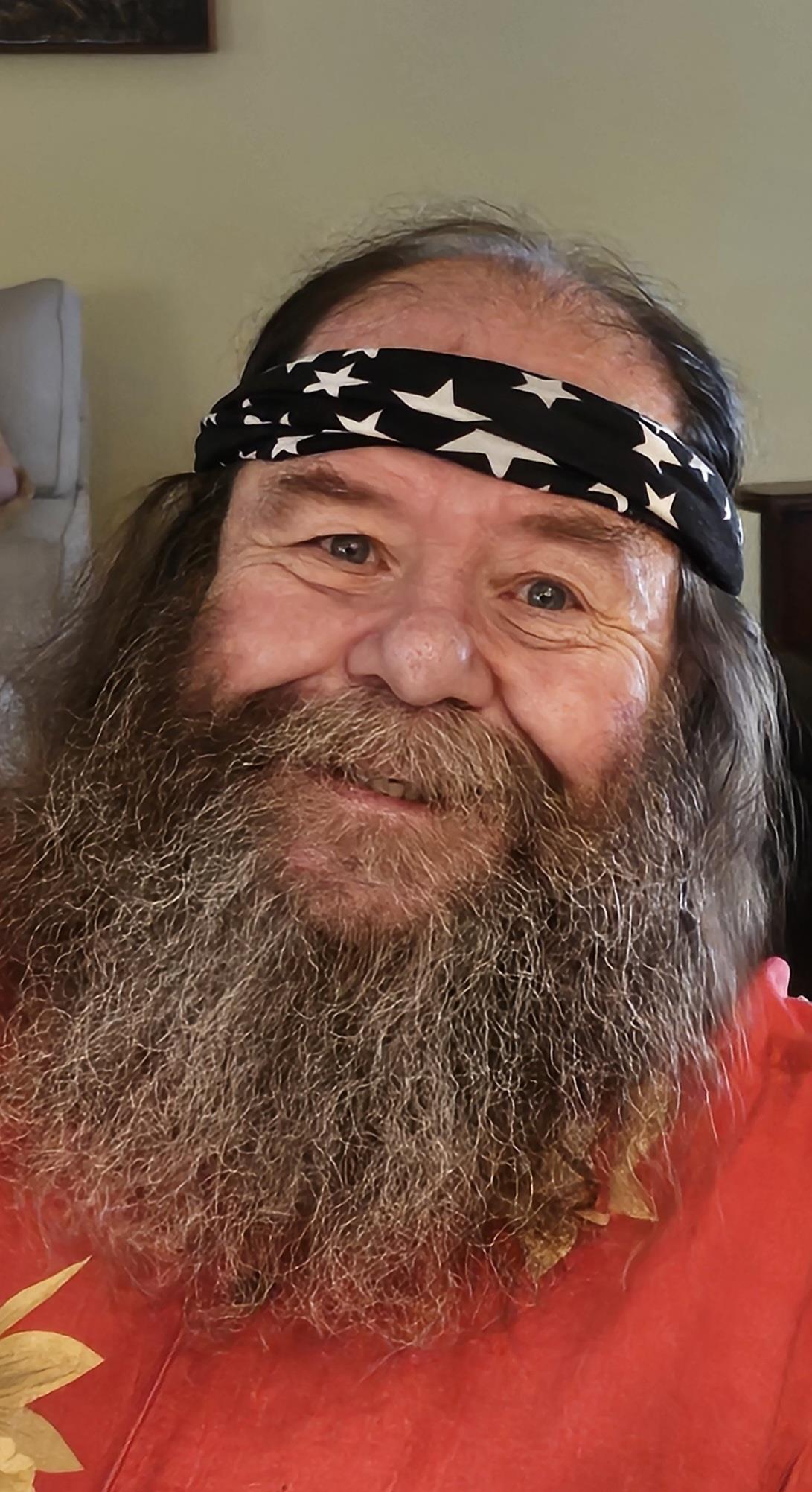 A man with a beard and a black headband