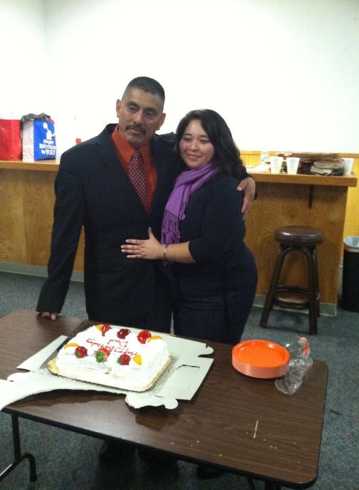 A man and woman standing next to a cake