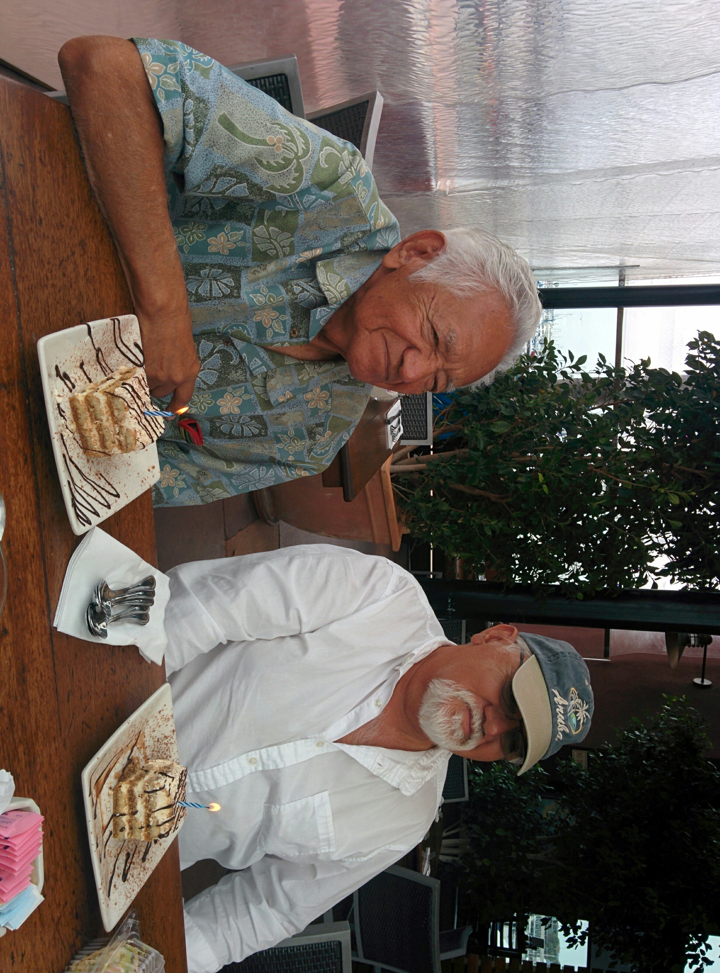 Two men sitting at a table with a cake