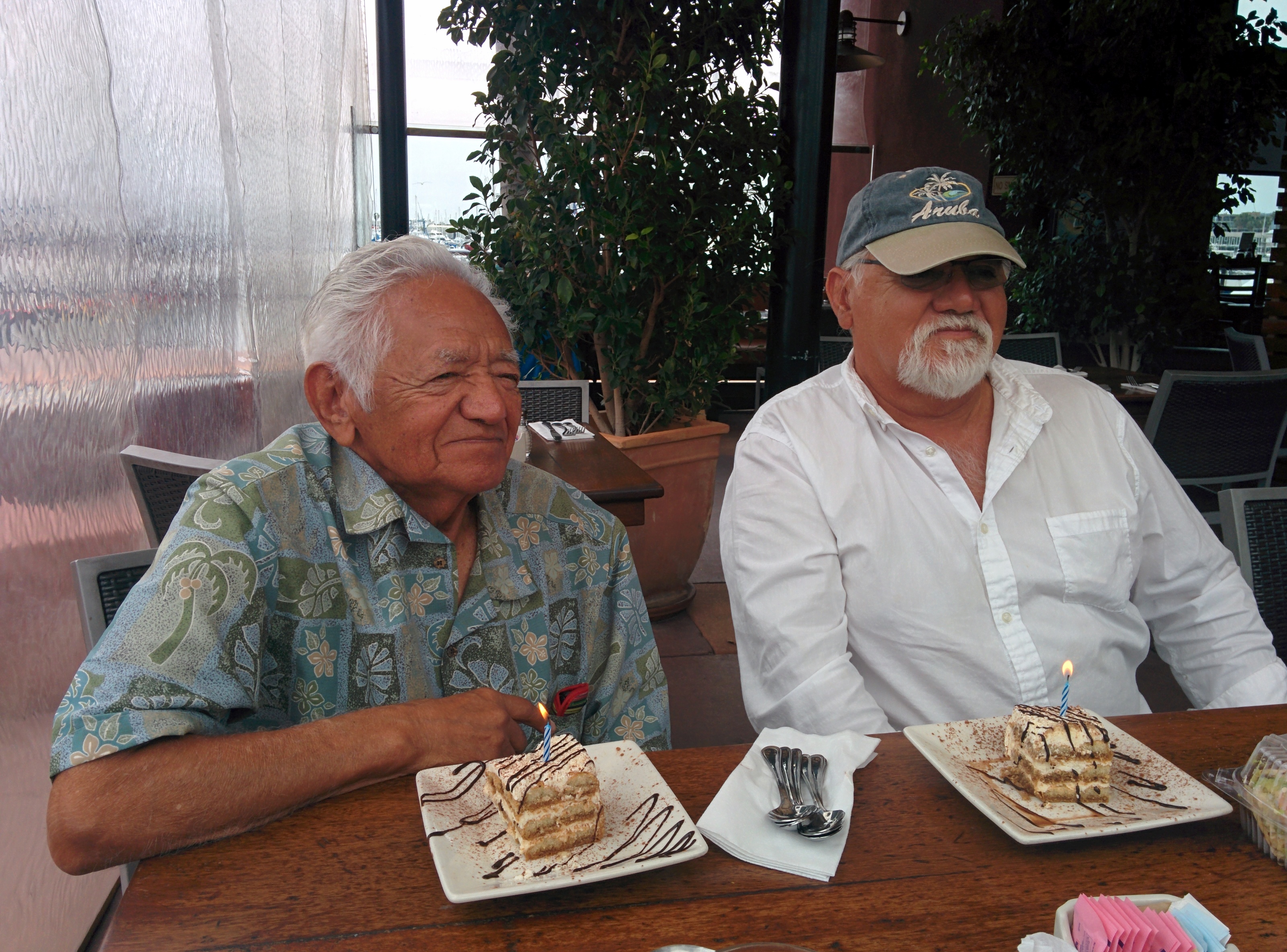 A couple of men sitting at a table with cakes