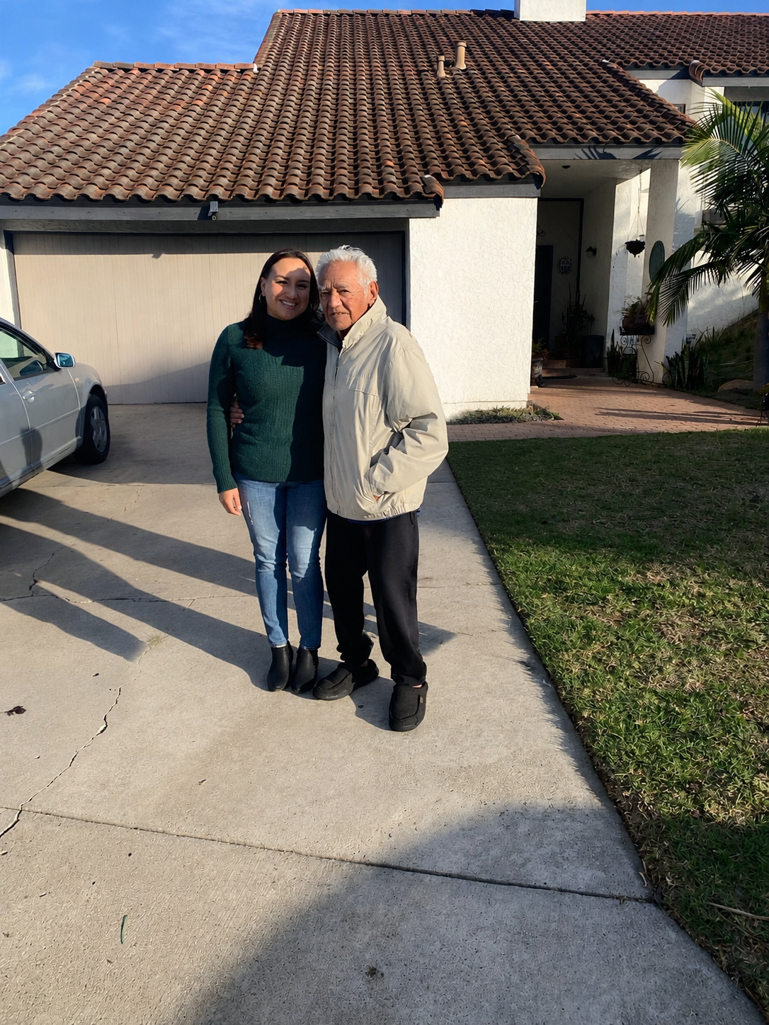 A man and woman standing together in front of a house