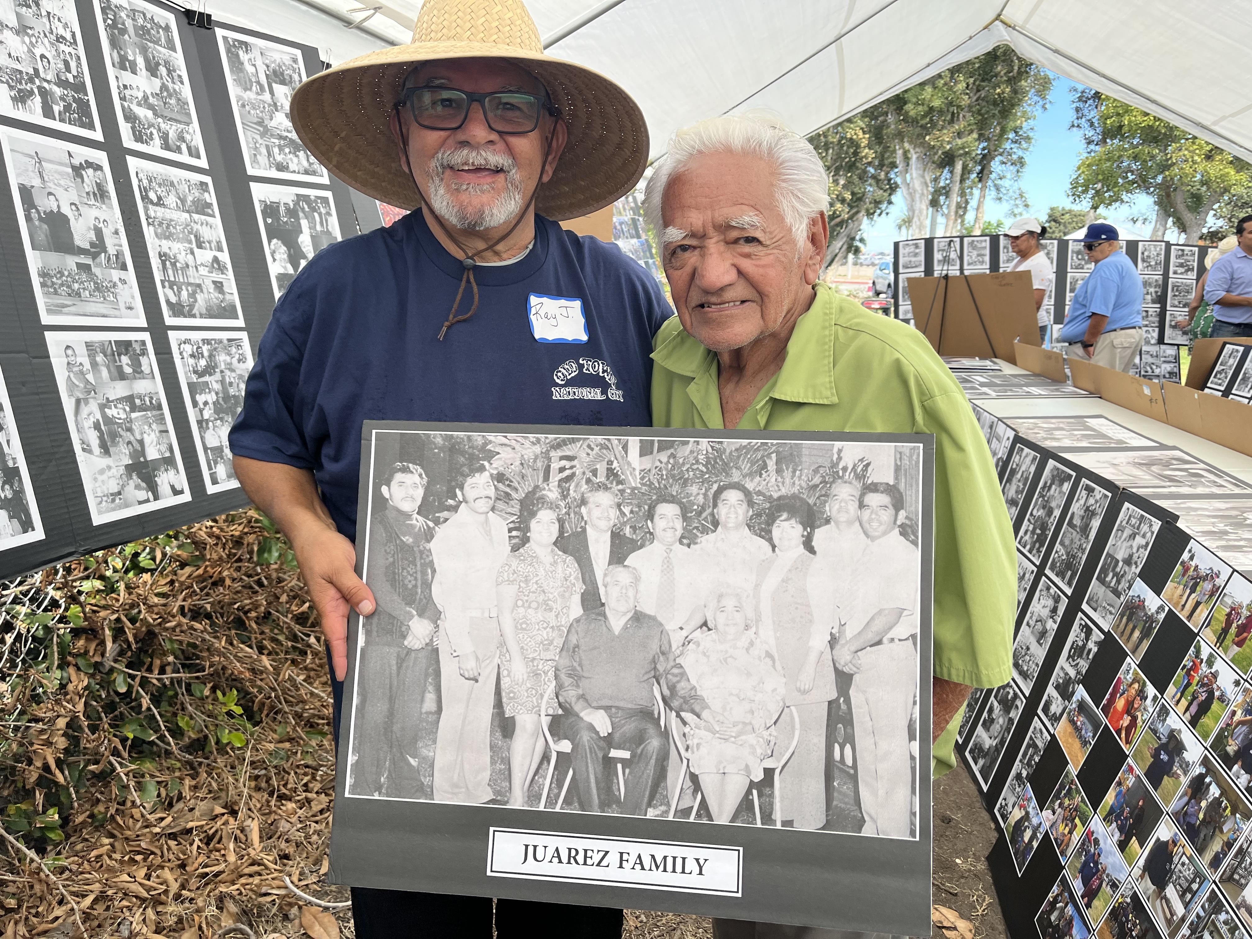 Two men holding a photo of a family